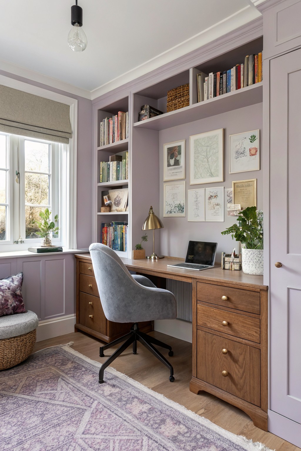 Cozy home office with soft lilac purple walls, built-in bookshelves, wooden desk, gray chair, plants, and artwork