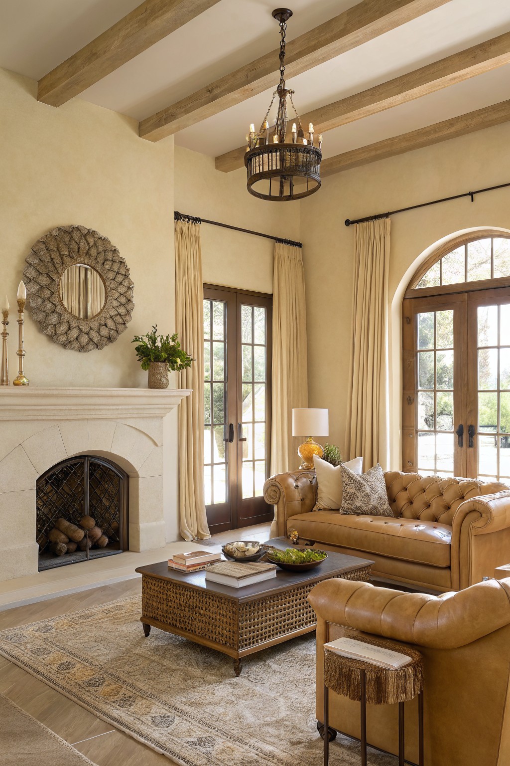 Cozy living room with warm beige walls, tan leather sofa, wood beams, and arched stone fireplace