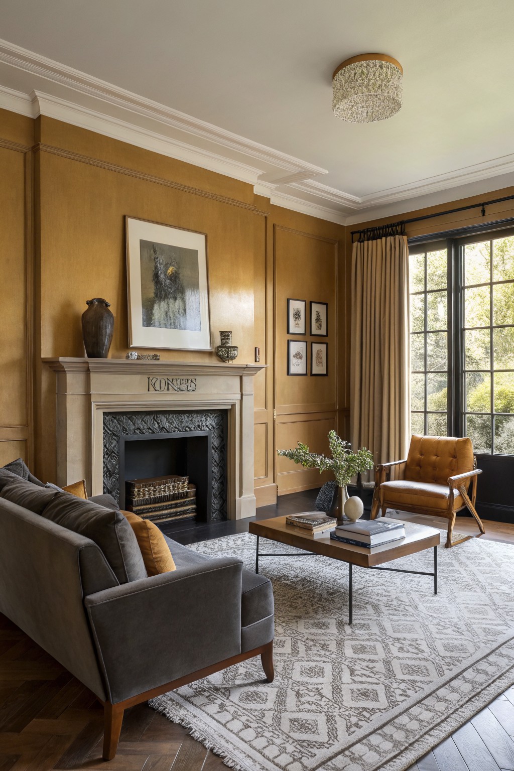 Living room with warm beige paneled walls, gray sofa, orange armchair, wood coffee table, and stone fireplace.