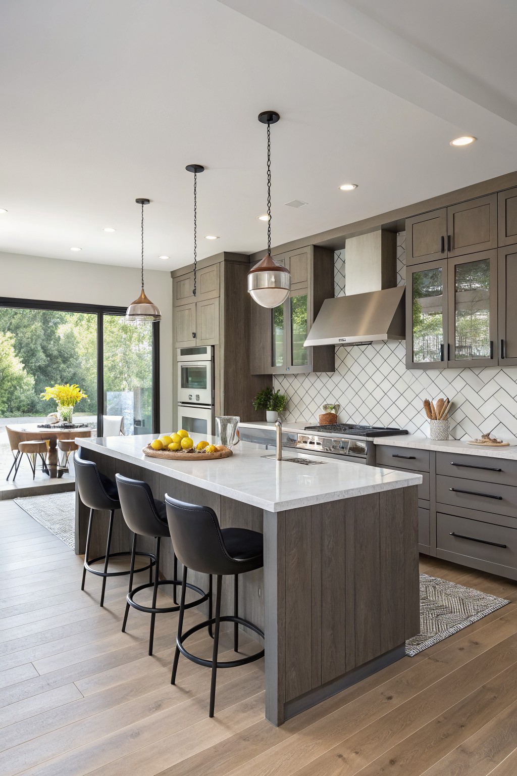 Modern kitchen featuring warm greige cabinets, white quartz island, herringbone tile backsplash, and oak flooring