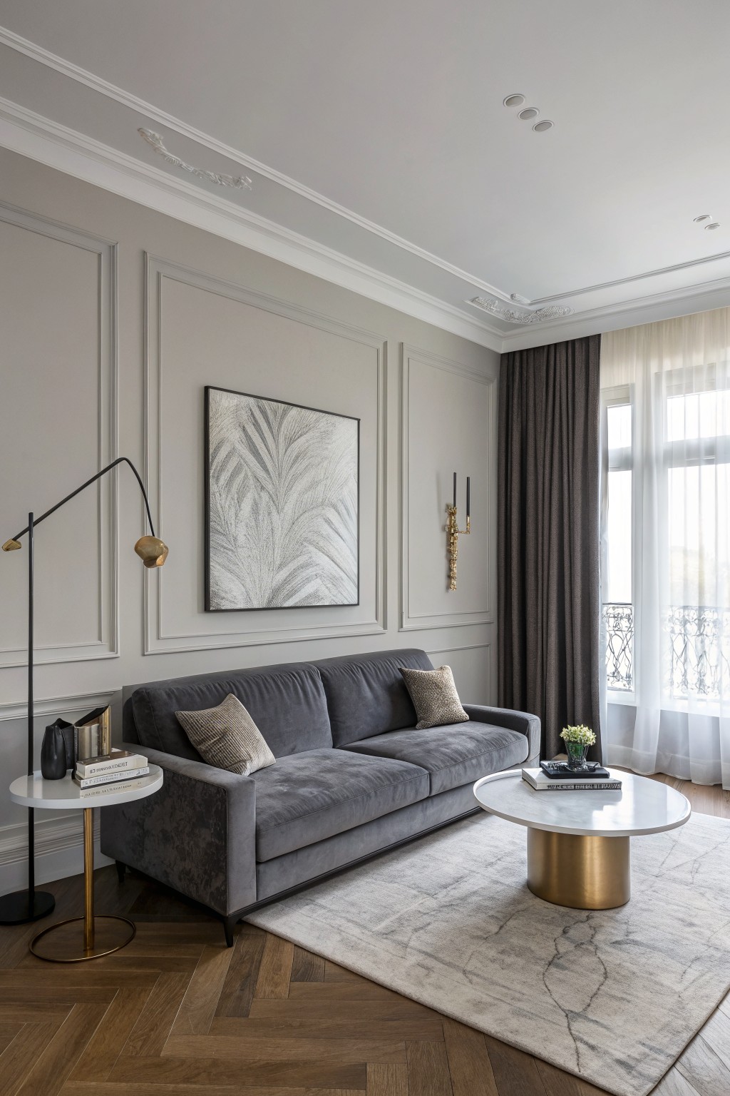 Elegant living room with soft greige paneled walls, gray velvet sofa, gold accents, and large windows with sheer curtains