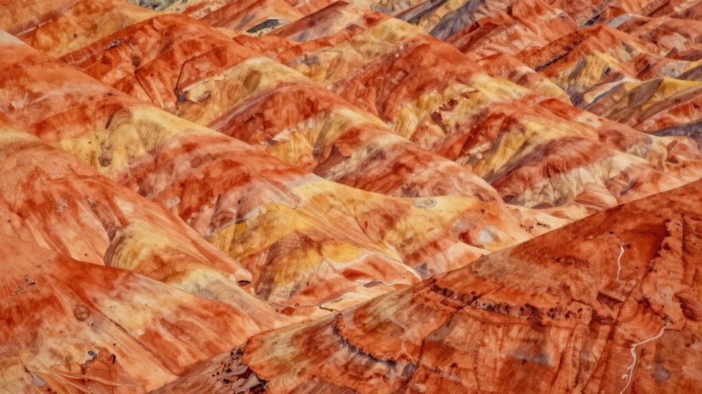 18 Earthy Abstract Painting Ideas for Warm Organic Interiors Eroded hills with vibrant layered patterns in orange, red, and beige hues.