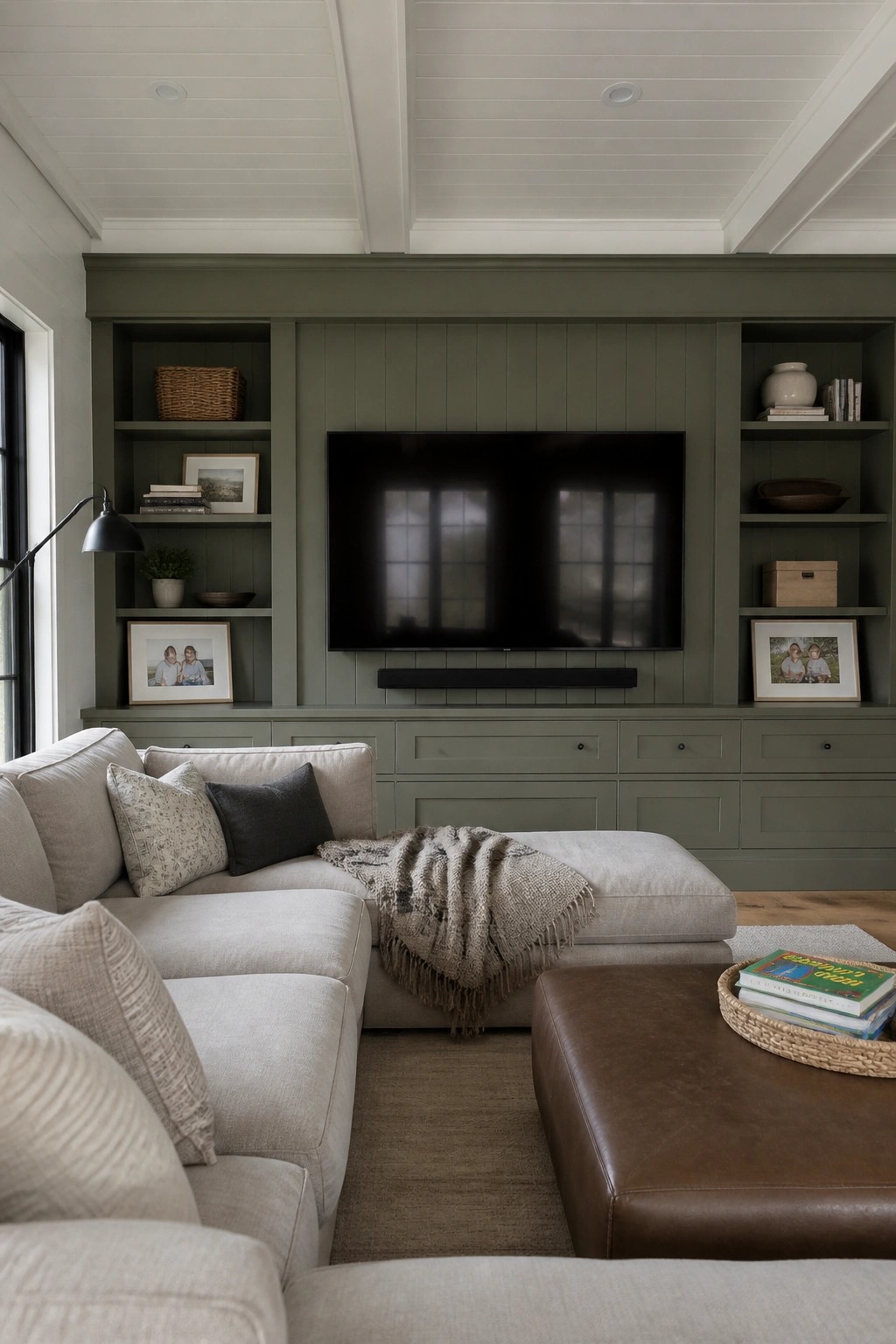 Built-in cabinetry and shelves painted in a muted sage green surround a wall-mounted TV.