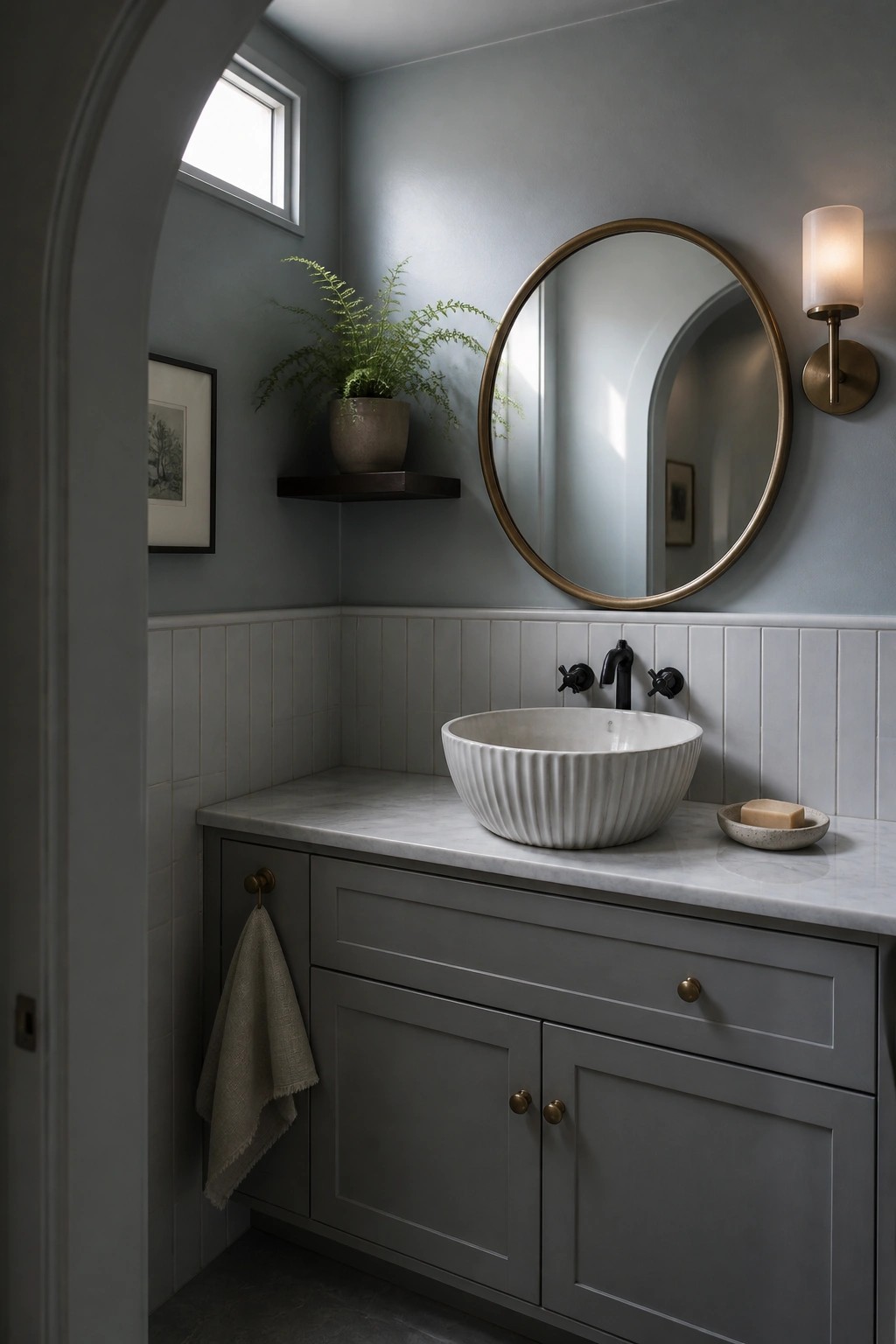 A bathroom with soft gray walls, beadboard wainscoting, and a marble vanity.