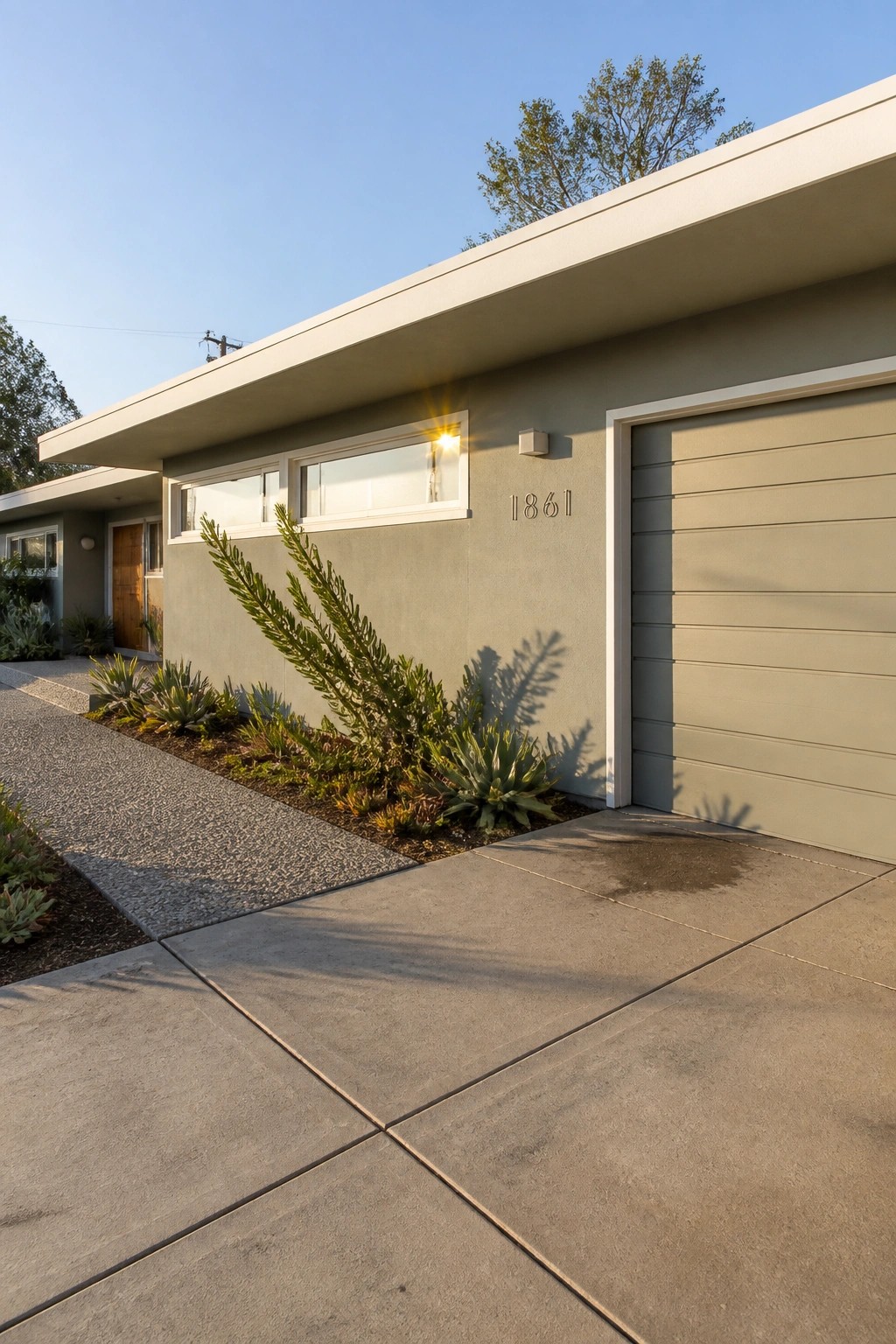 A house exterior painted in soft sage green with white trim around the windows and garage door.