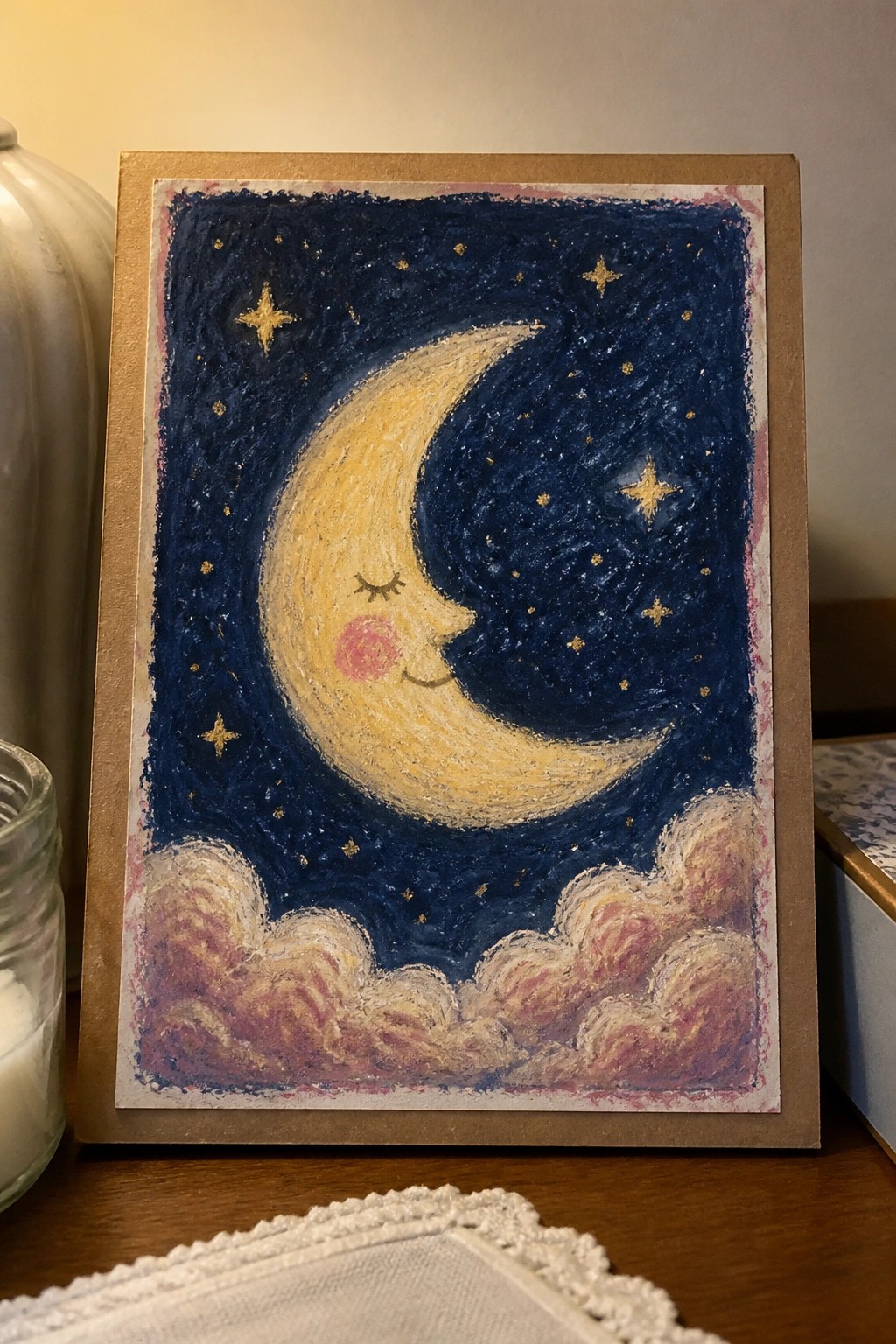 Framed pastel drawing of smiling crescent moon with golden stars and fluffy clouds.