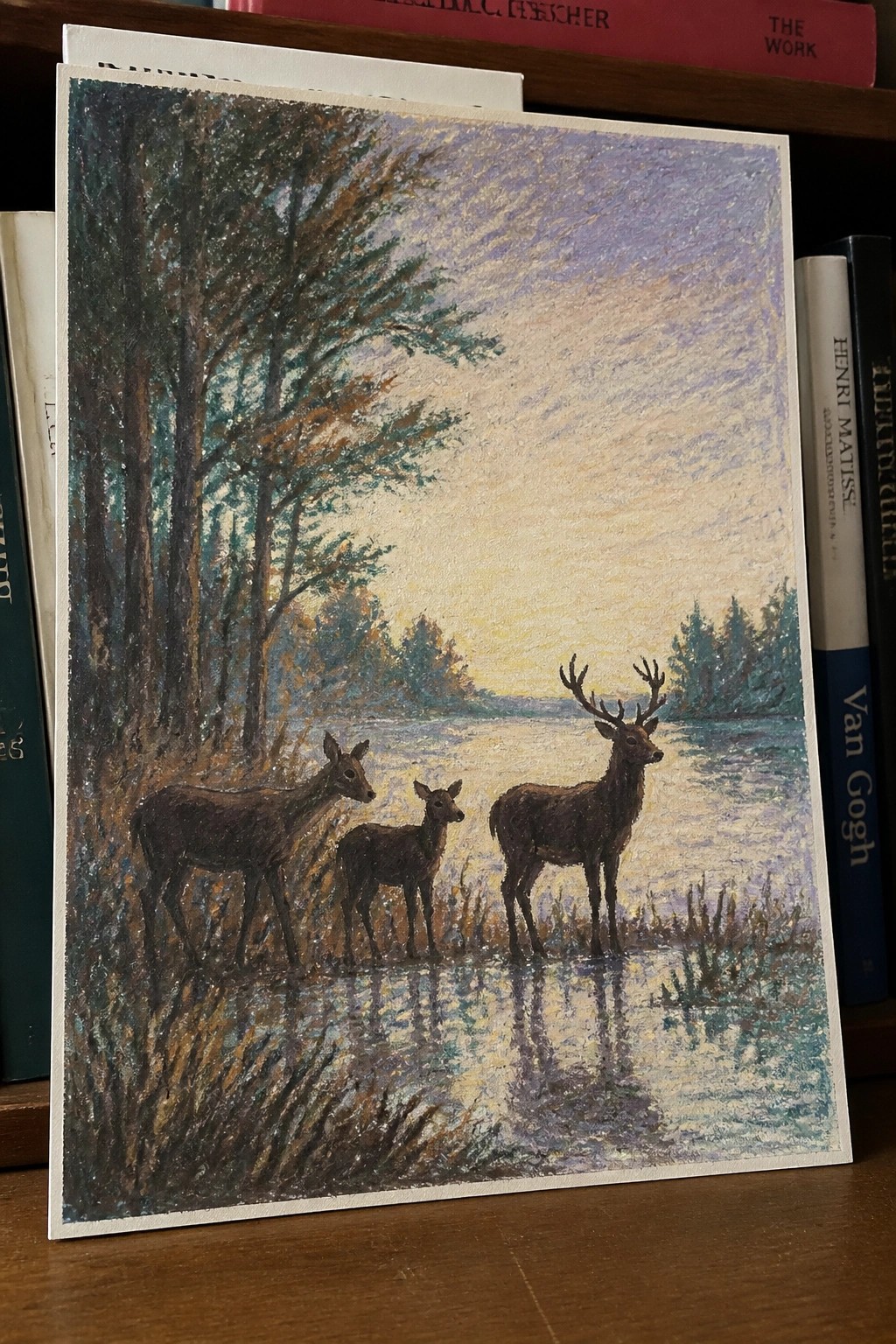 A painting of three deer standing by a lake at sunset, with trees on the left and reflections in the water.