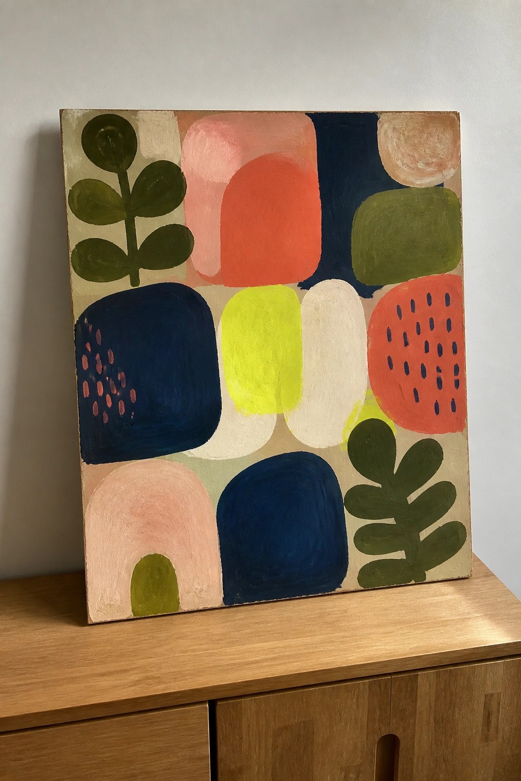Colorful abstract painting with geometric shapes and leaf motifs on wooden cabinet