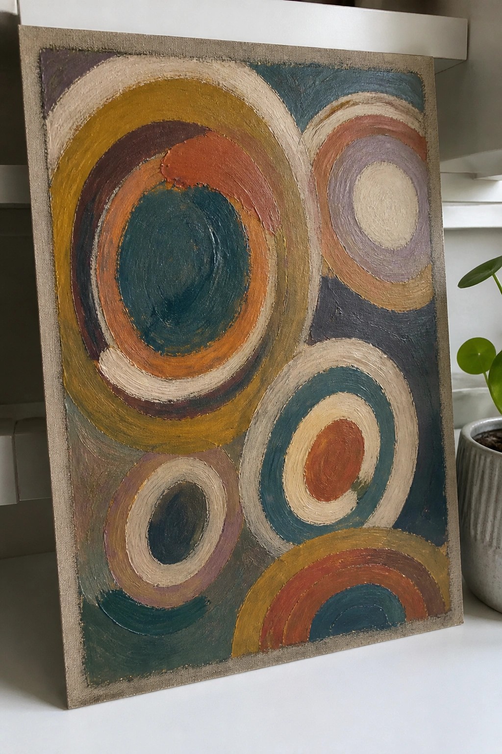 Abstract painting of overlapping concentric circles in teal, orange, and yellow tones.