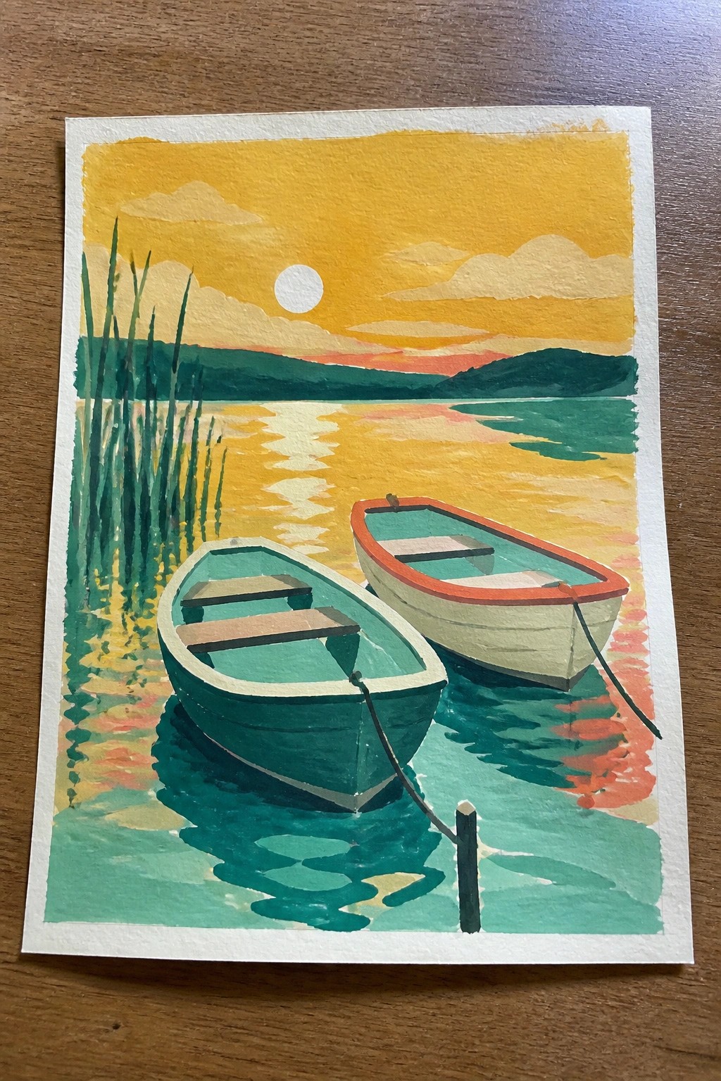 Two rowboats tied to a post on a vibrant sunset lake with reeds and reflections