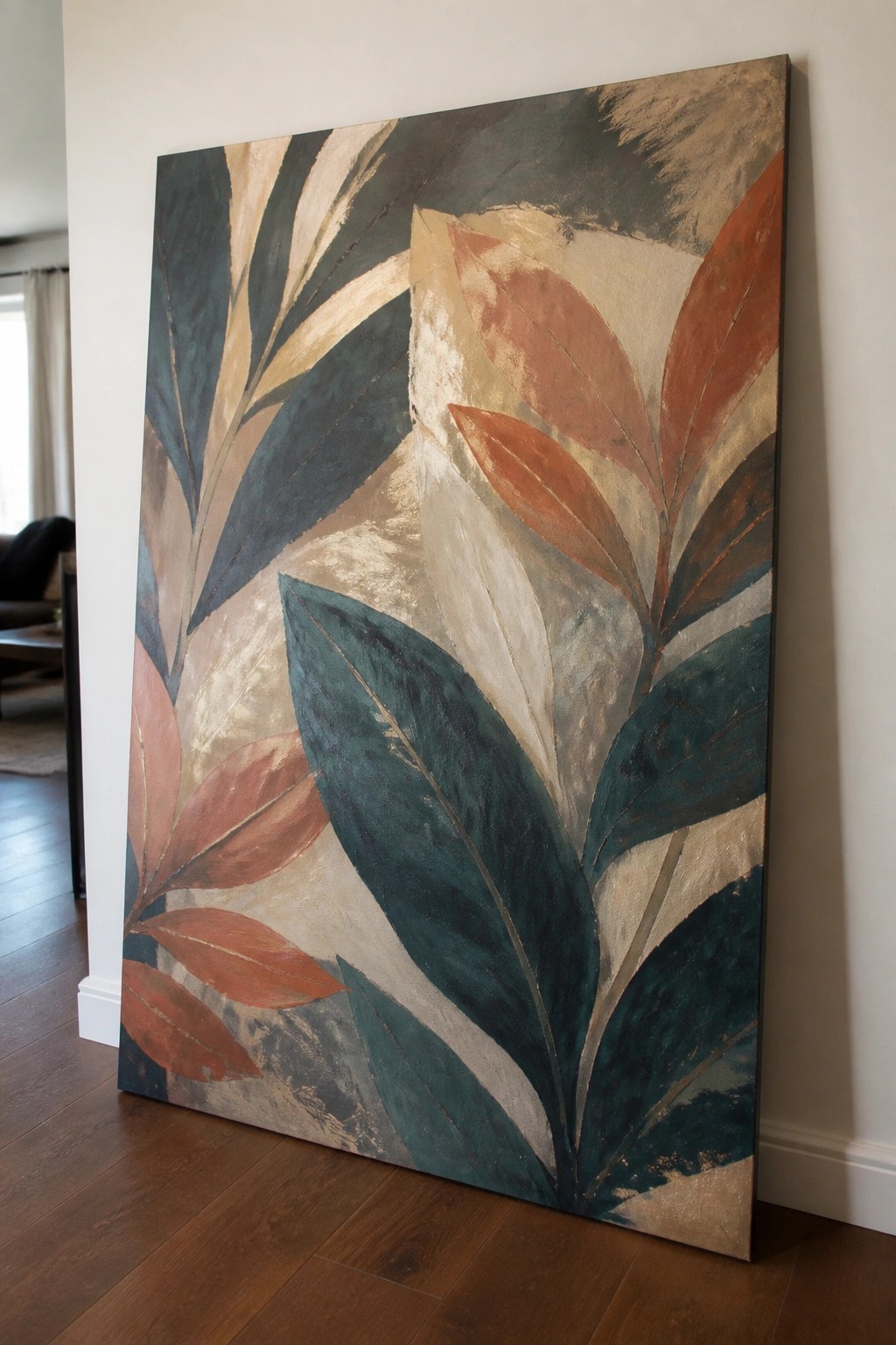 Abstract painting of teal and rust leaves on textured canvas leaning against wall on wood floor