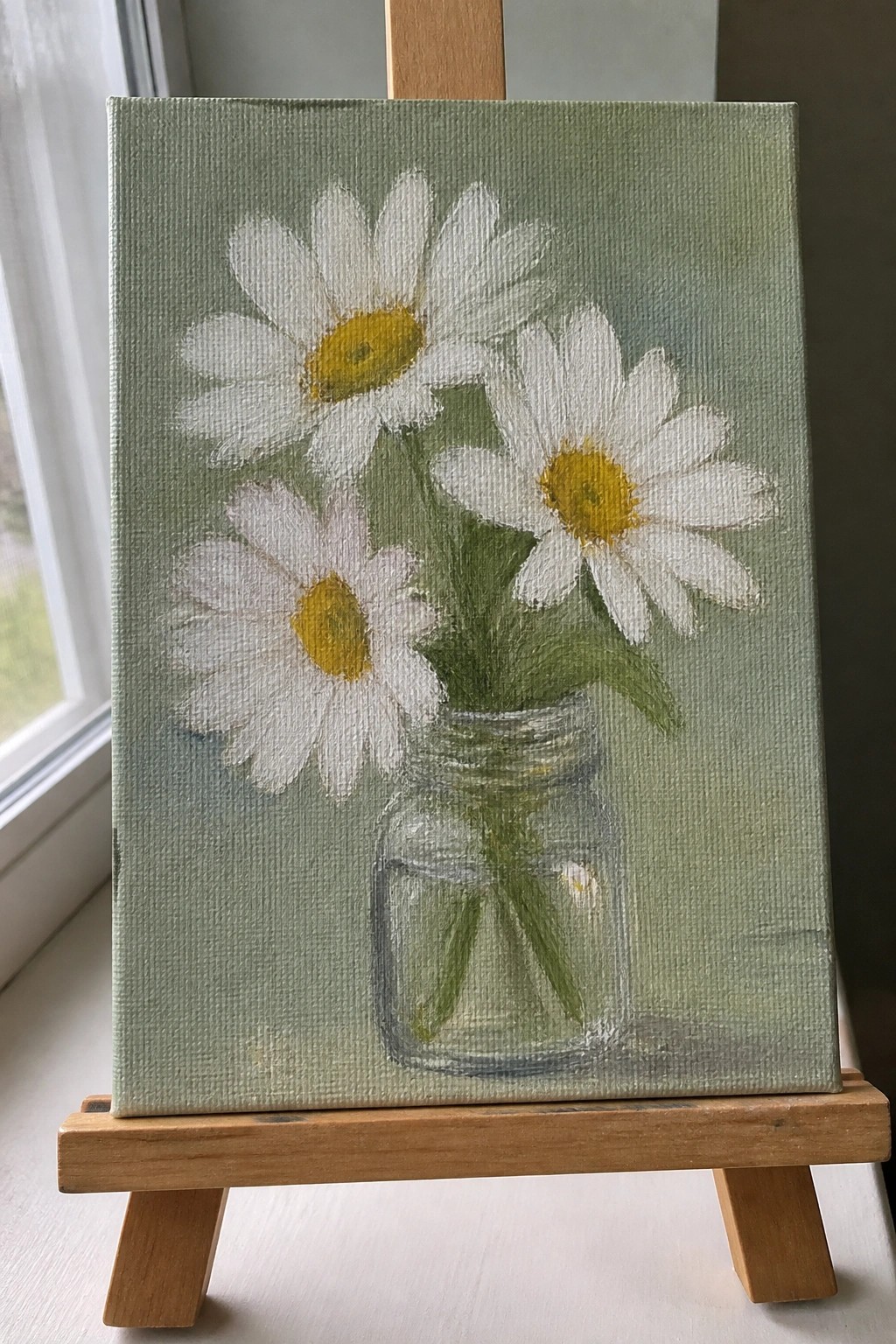 Painting of three white daisies in a glass jar on a wooden easel