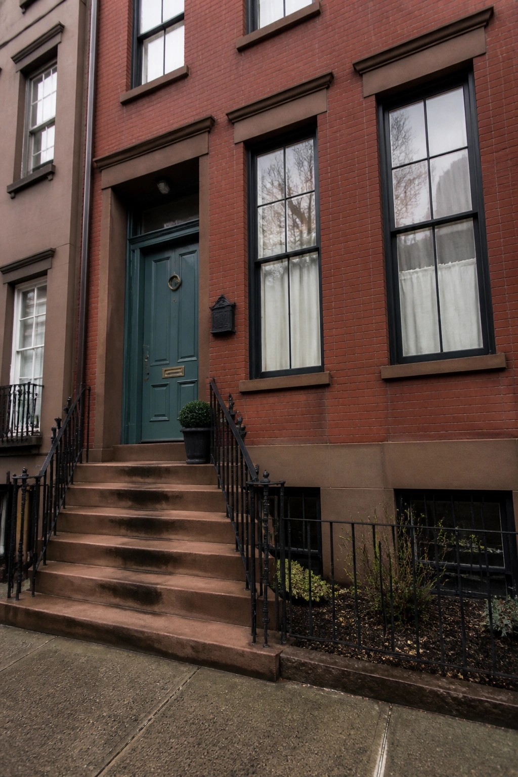 A deep green front door on a red brick row house.