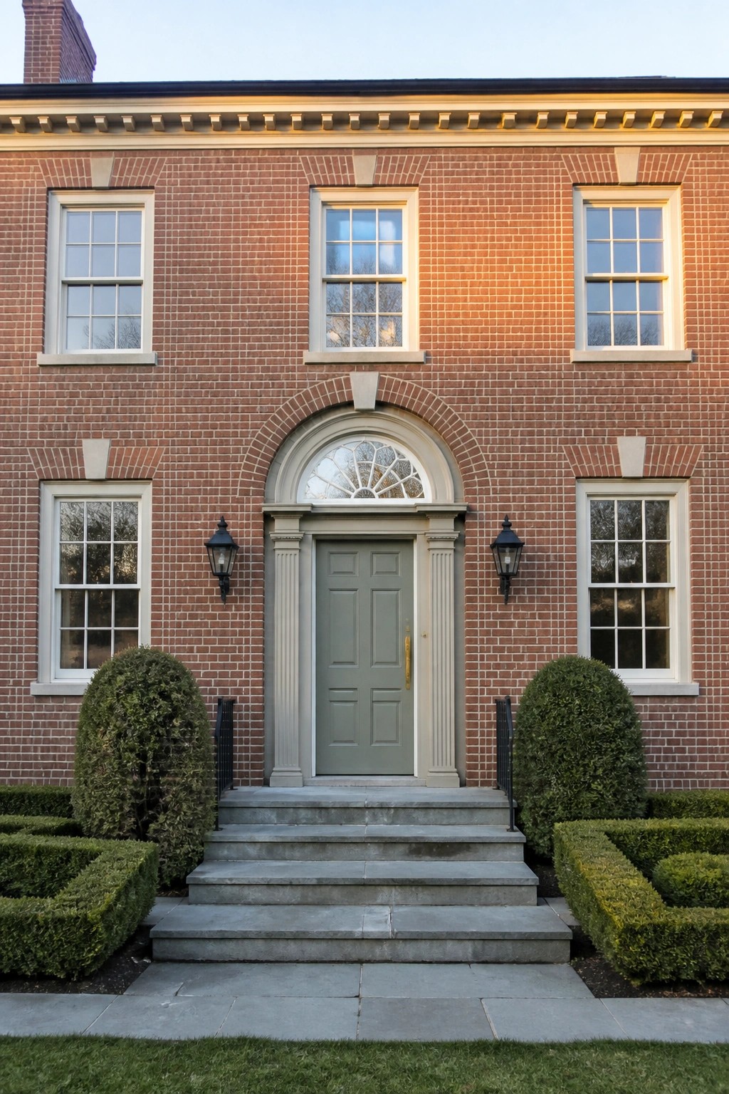 Red brick home entrance with sage green door, arched transom, and stone steps
