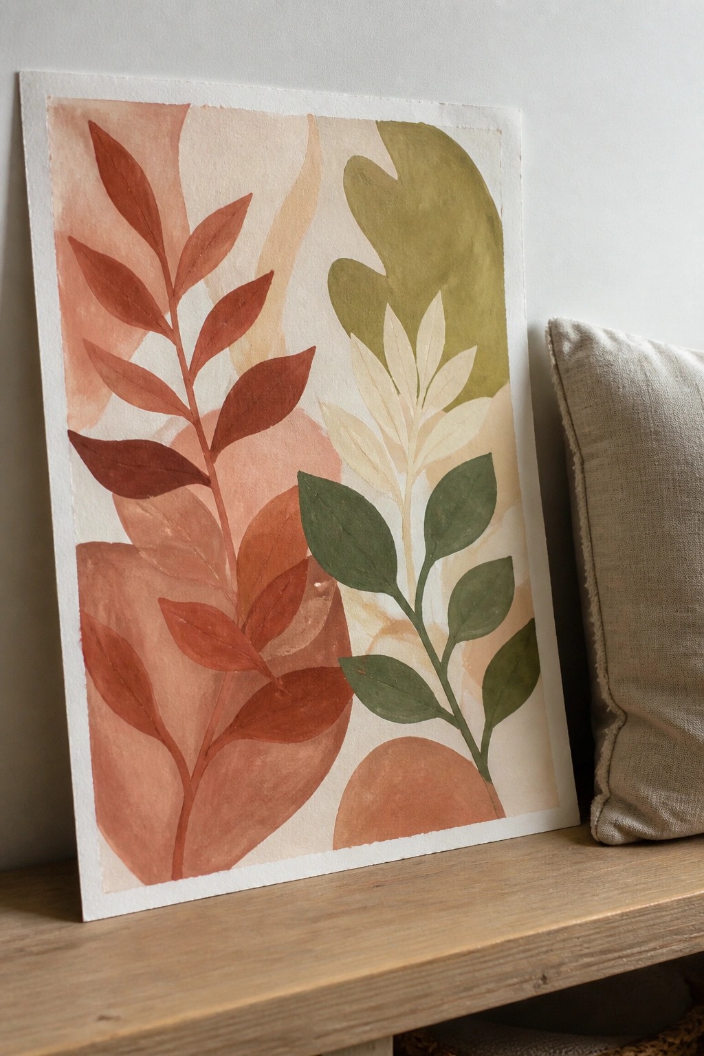 Watercolor painting of abstract leaves in terracotta, green, and beige tones on wood.