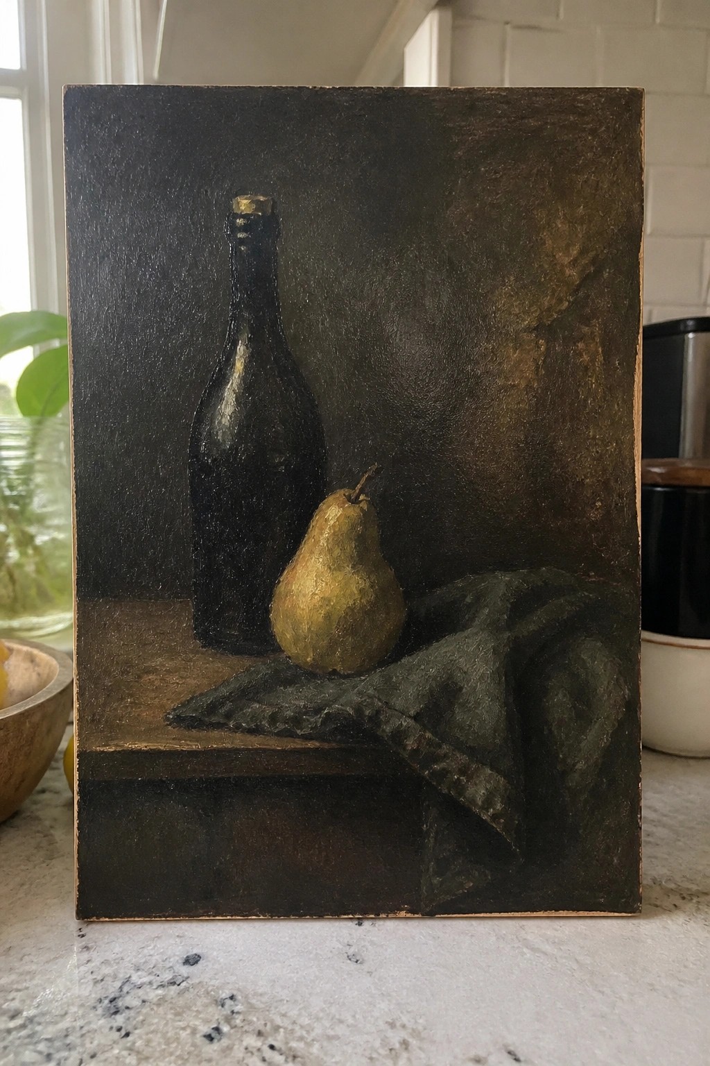 Still life painting of dark bottle, yellow pear, and draped cloth on wood.