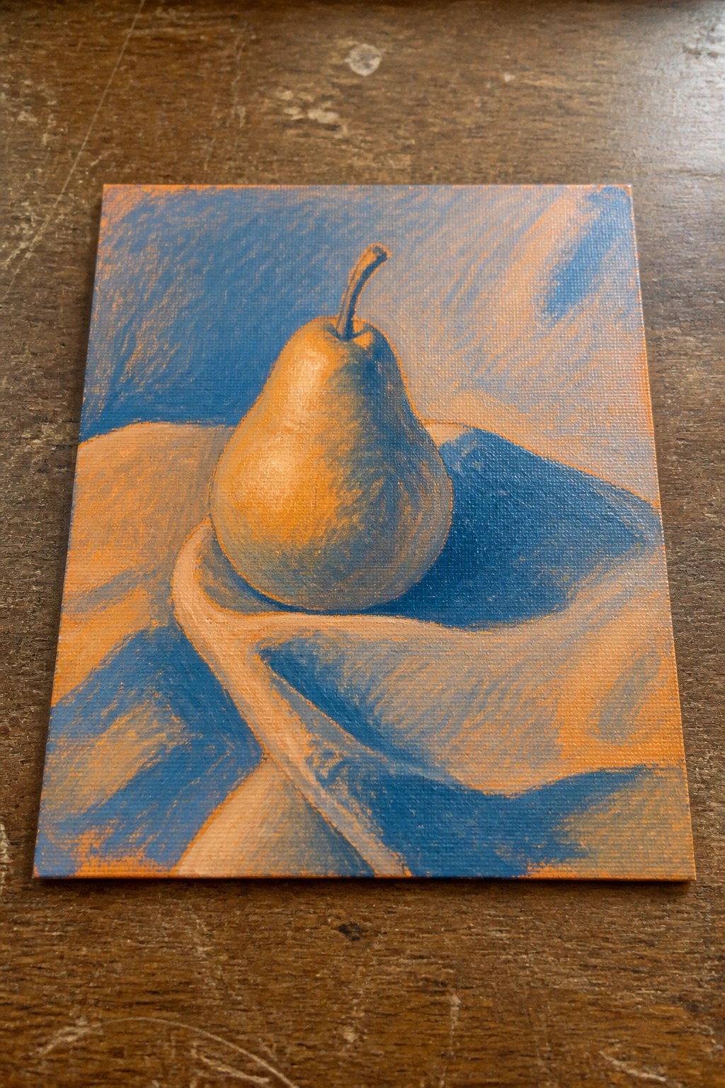 Golden pear on blue draped cloth in orange-blue still life painting.
