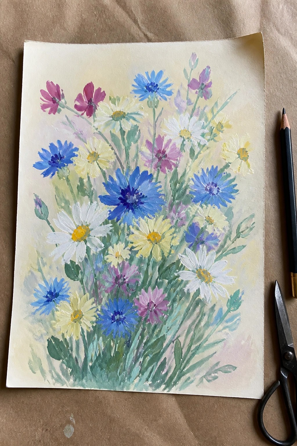 Watercolor painting of blue cornflowers, daisies, and wildflowers with pencil and scissors