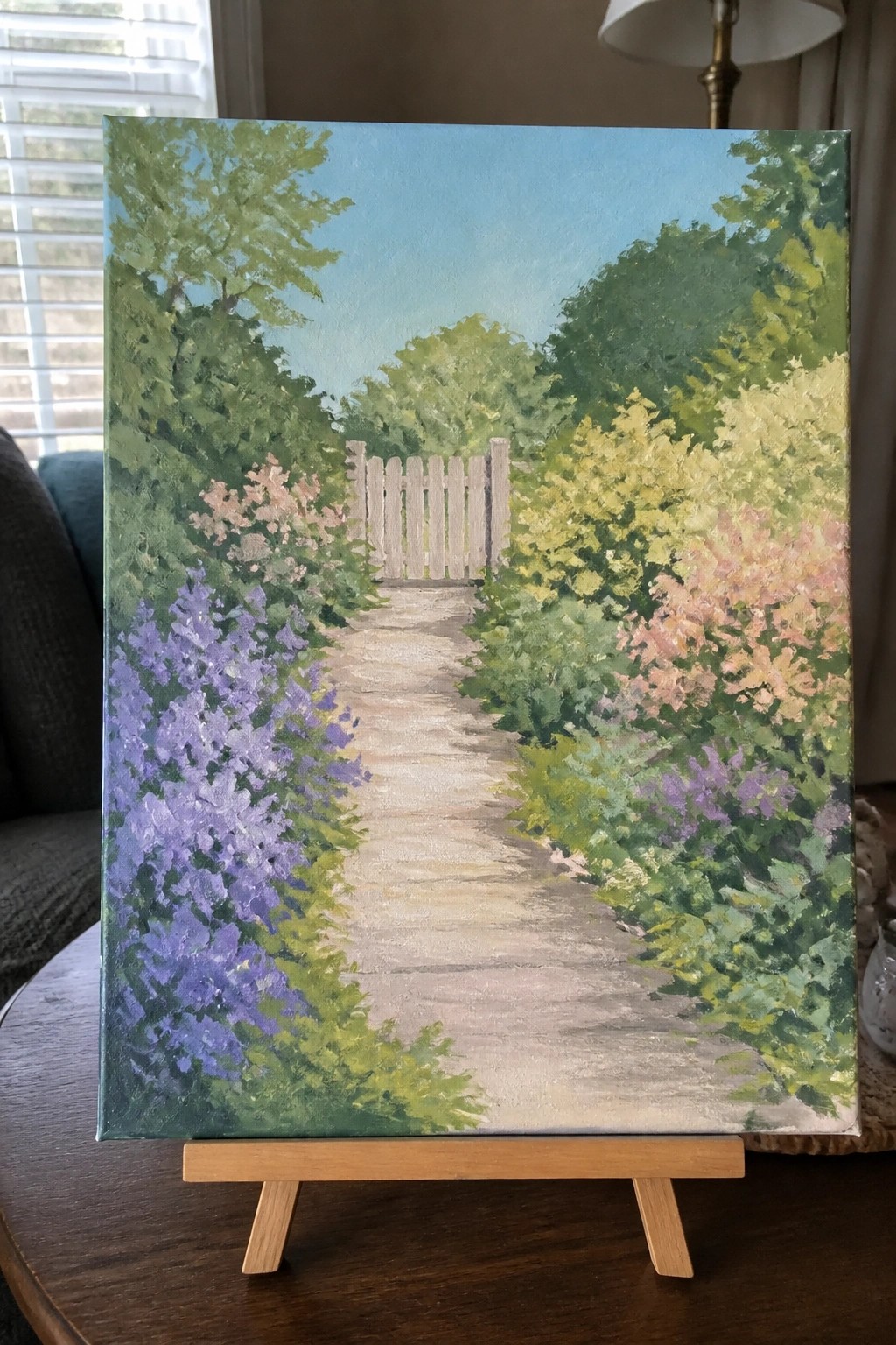 Vibrant painting of a flower-lined garden path leading to a wooden gate under blue sky.