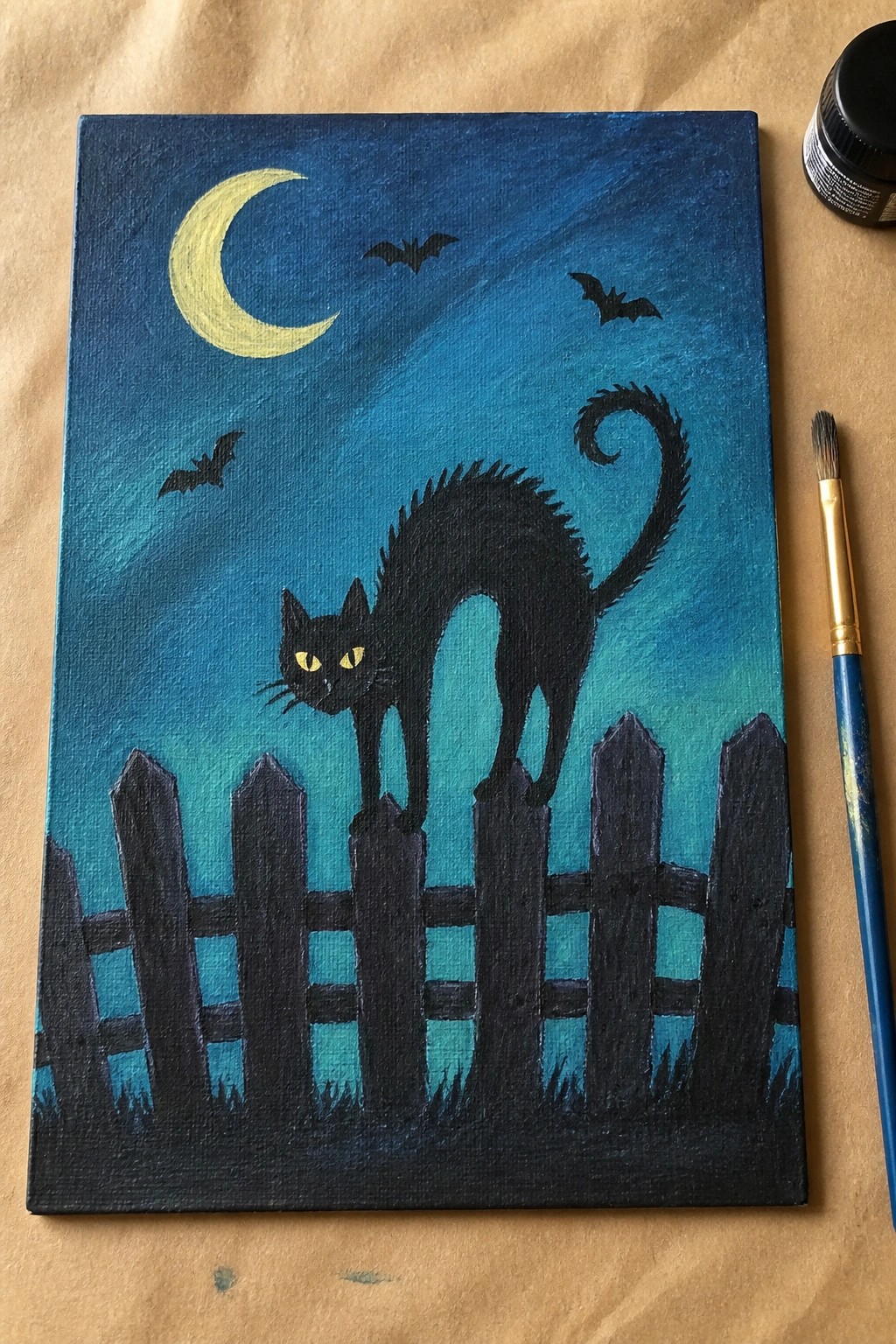 Black cat with yellow eyes on fence under crescent moon with bats in blue sky