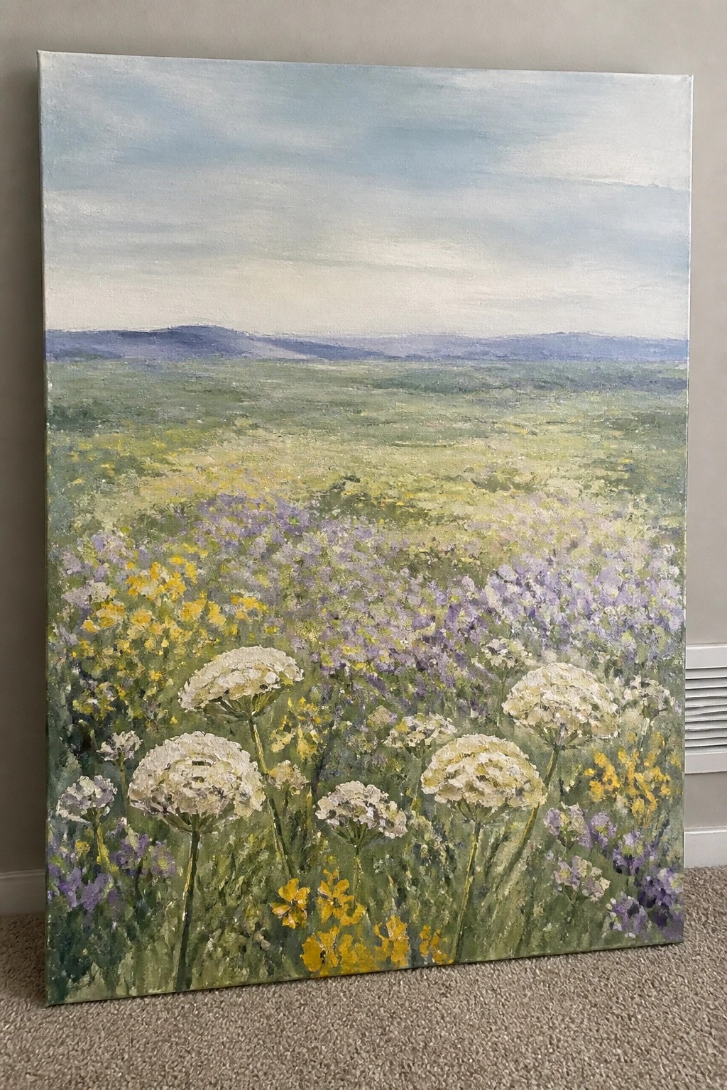 Acrylic painting of a wildflower meadow with white, yellow, and purple flowers in the foreground and rolling hills in the distance.
