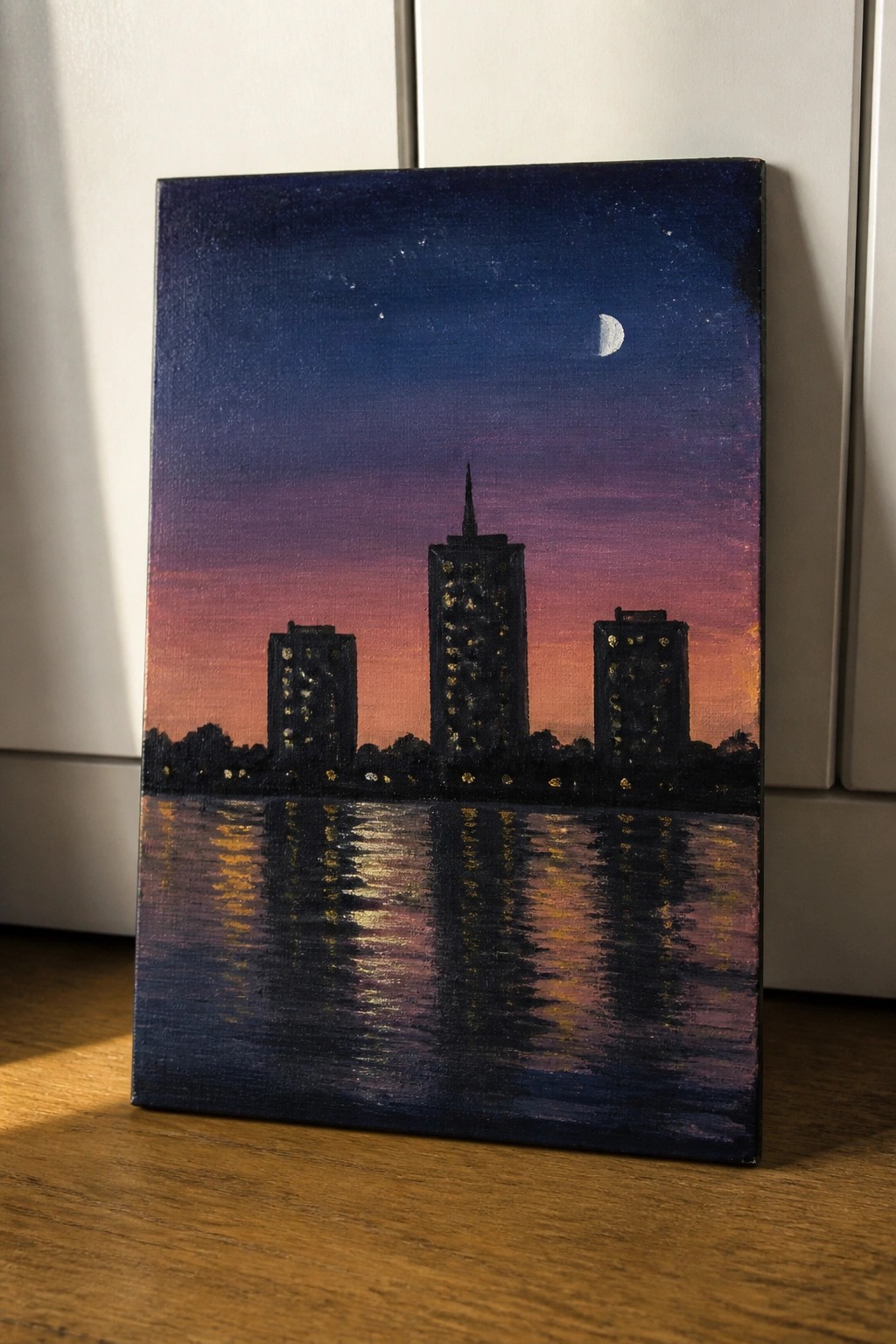 Three illuminated skyscrapers reflected in water under starry purple-orange dusk sky