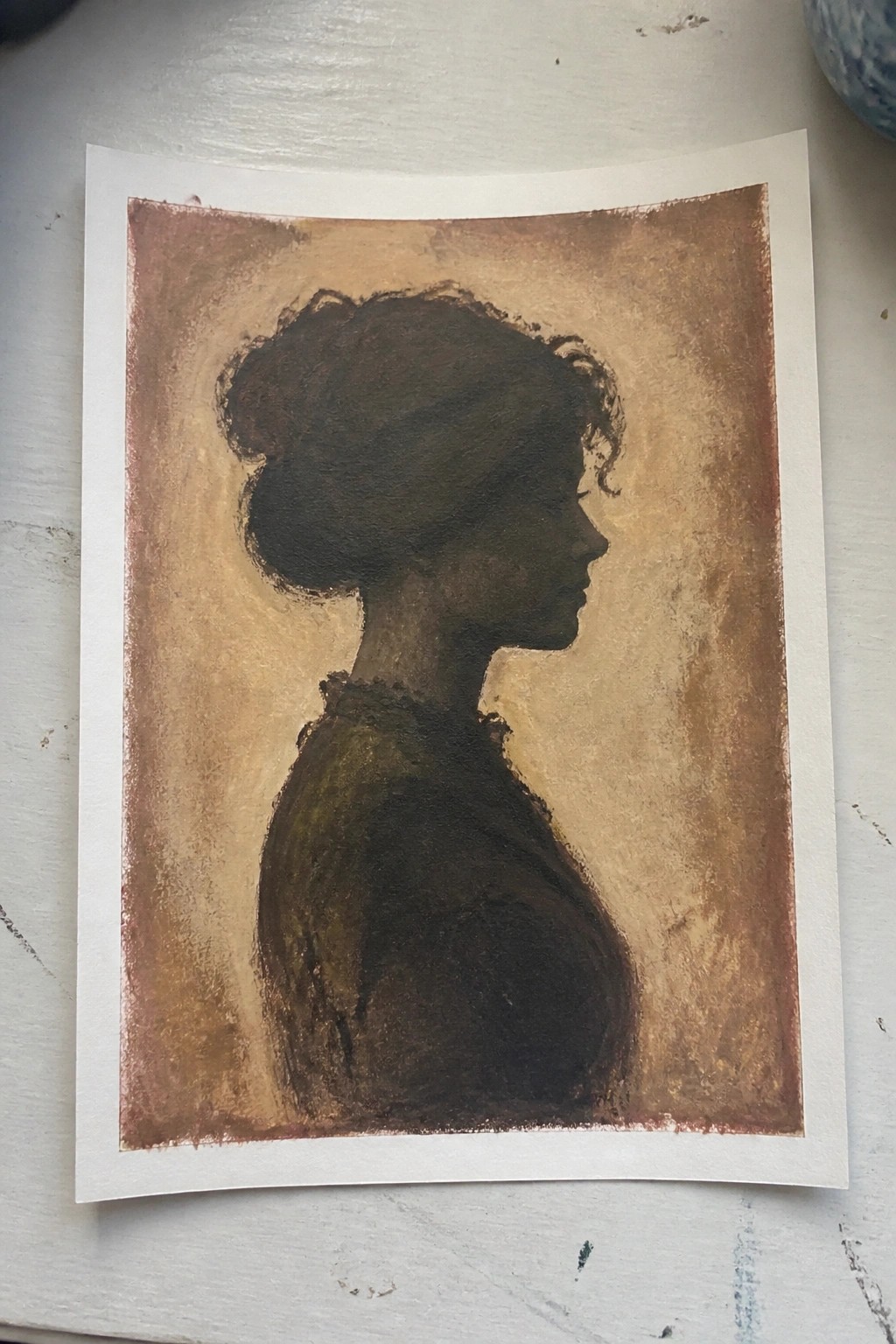 Silhouette of a woman in profile with hair in a bun against textured brown background