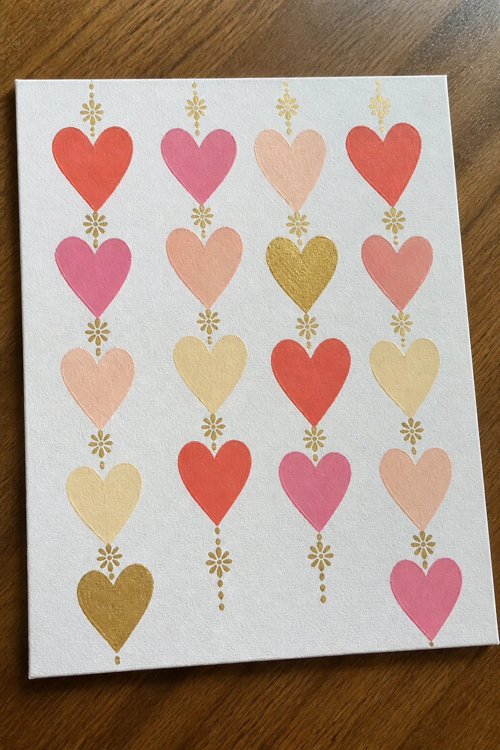 Colorful rows of painted hearts in red, pink, gold with floral accents on canvas