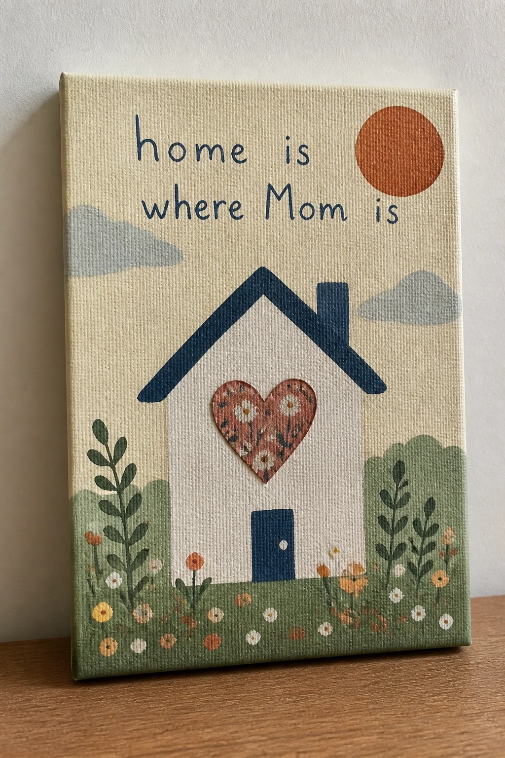 Canvas painting of house with floral heart, sun, clouds, plants and Mom quote