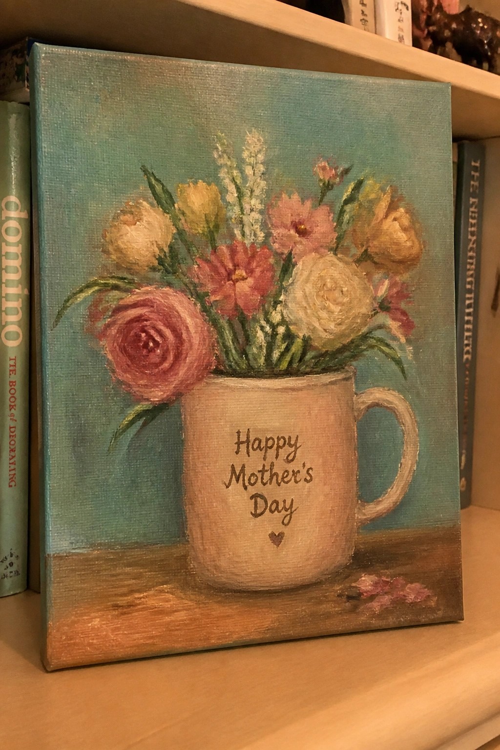 Painting of colorful flowers in a mug reading Happy Mother's Day on a shelf.