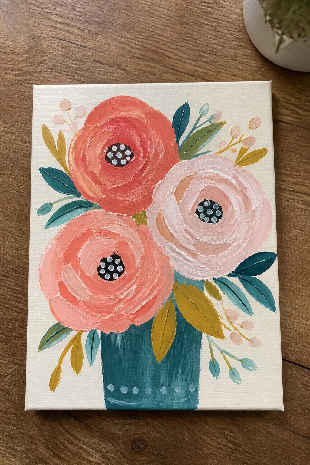Colorful floral painting with three blooms in a teal vase on wood