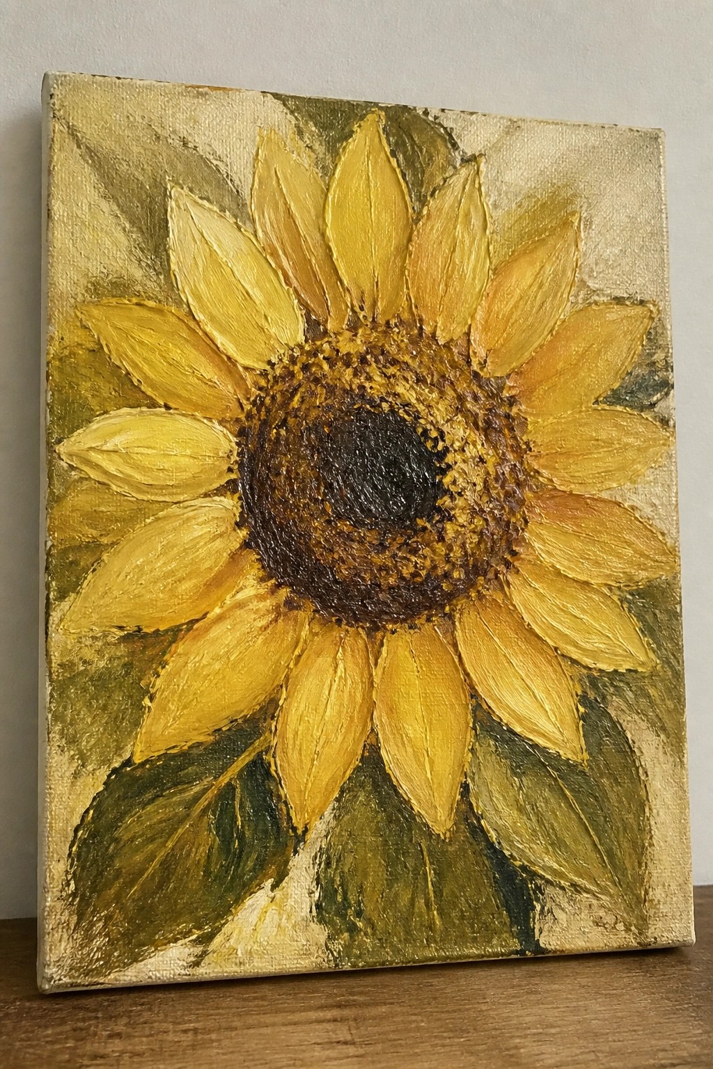 Thickly textured painting of a large yellow sunflower with dark center on gold background