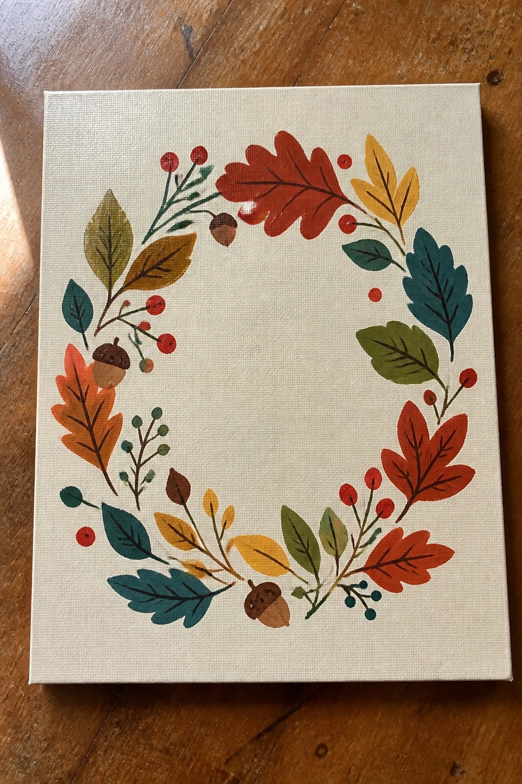 Colorful autumn wreath with red, orange, yellow leaves, acorns, and berries on canvas.