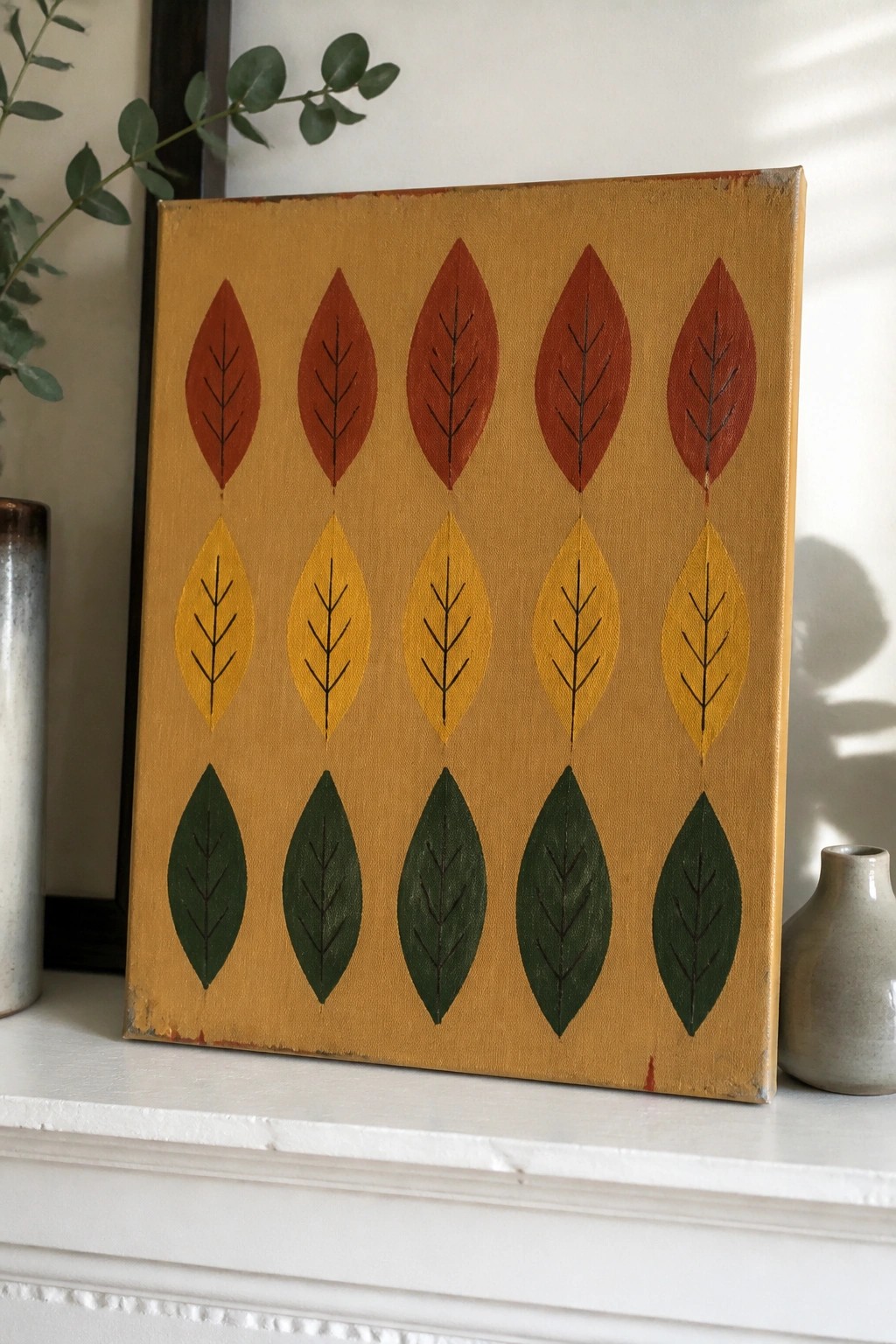 Yellow canvas with rows of red, yellow, and green painted leaves on a shelf