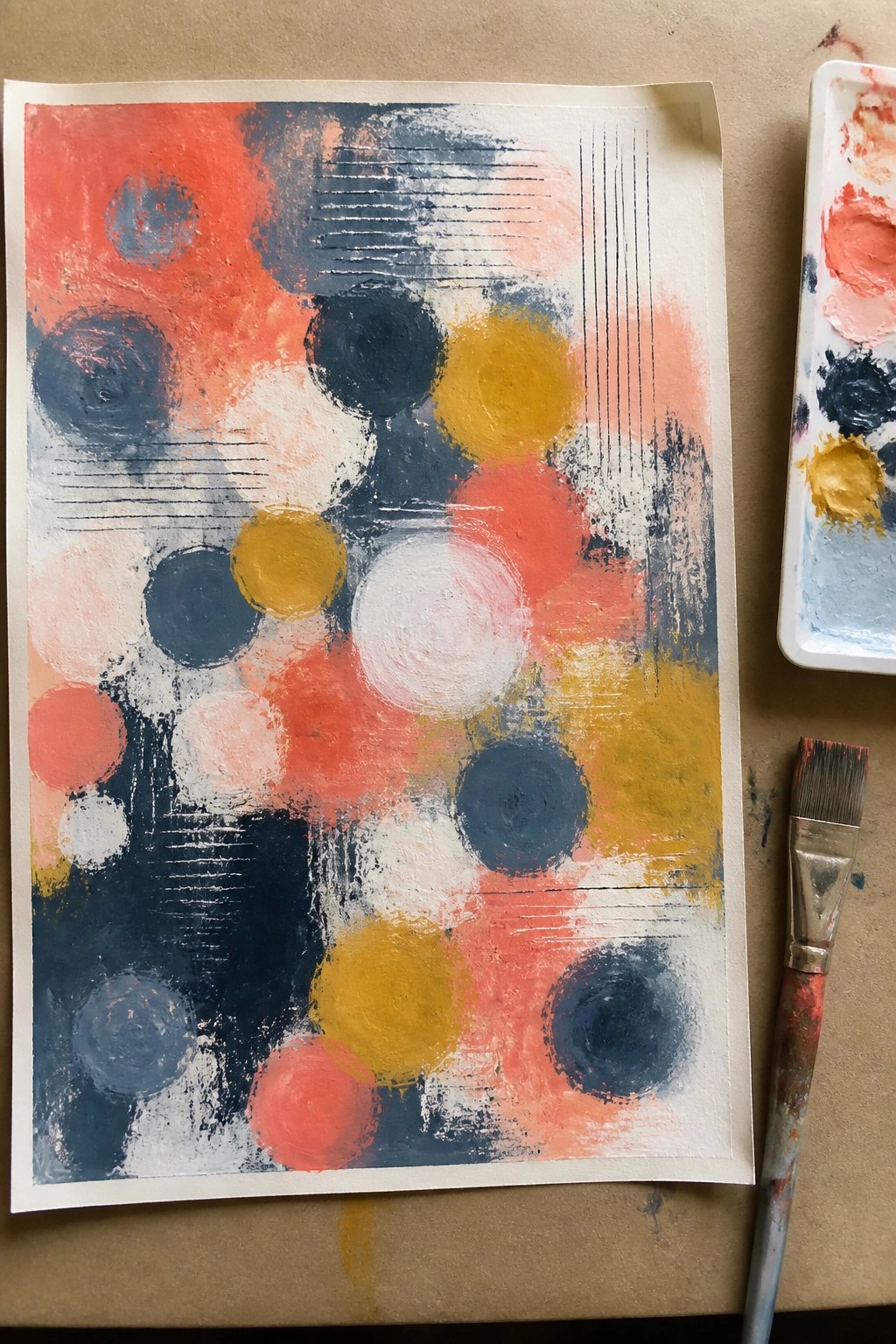 Abstract painting with red, blue, and yellow circles beside palette and brush.