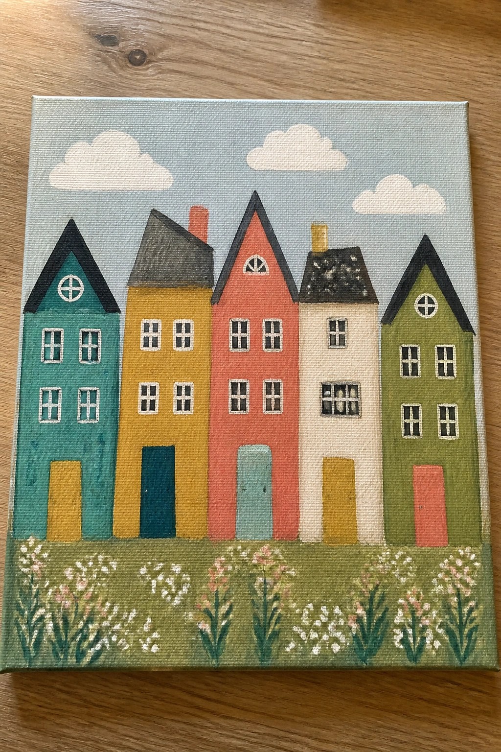 Colorful houses with pointed roofs under a blue sky above a field of flowers