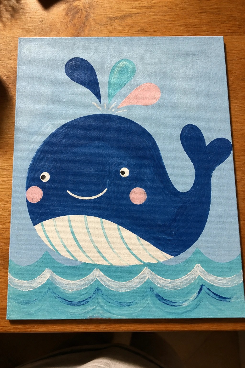 Cute cartoon blue whale with pink cheeks spouting water above teal waves
