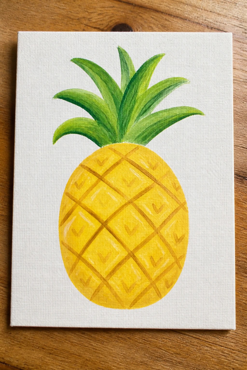 Yellow pineapple with brown grid pattern and green crown on white canvas