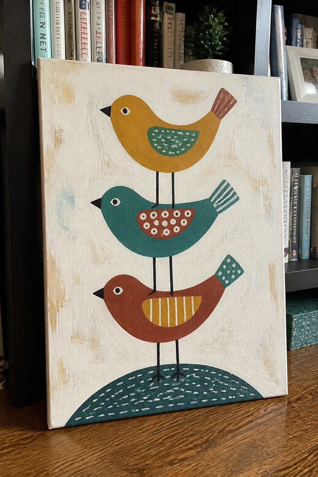 Three stacked colorful birds with patterned bellies on an off-white canvas.