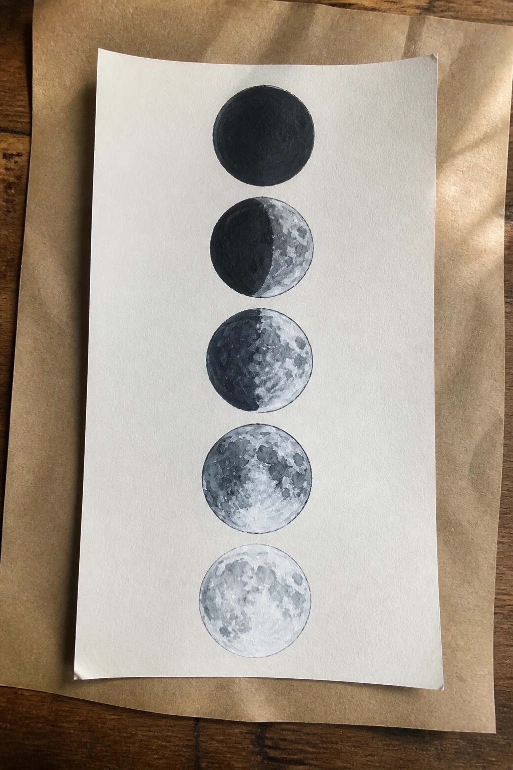 Watercolor painting of five moon phases from new to full vertically on paper
