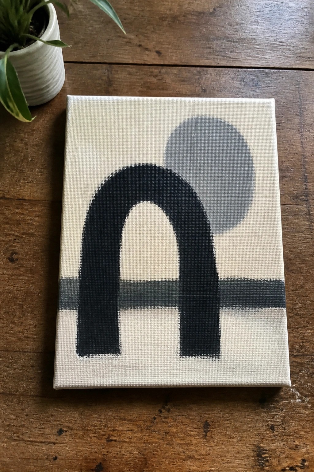 Minimalist abstract painting with black arch, gray circle, and horizontal line on canvas
