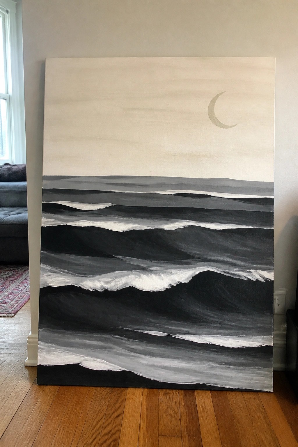 Large abstract painting of black waves with white foam and crescent moon indoors