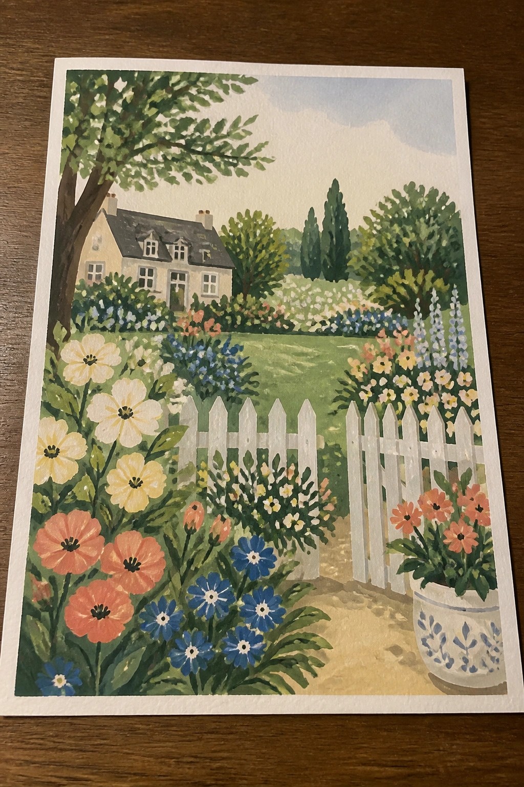 Watercolor painting of vibrant cottage garden with white picket fence, blooming flowers, and path.