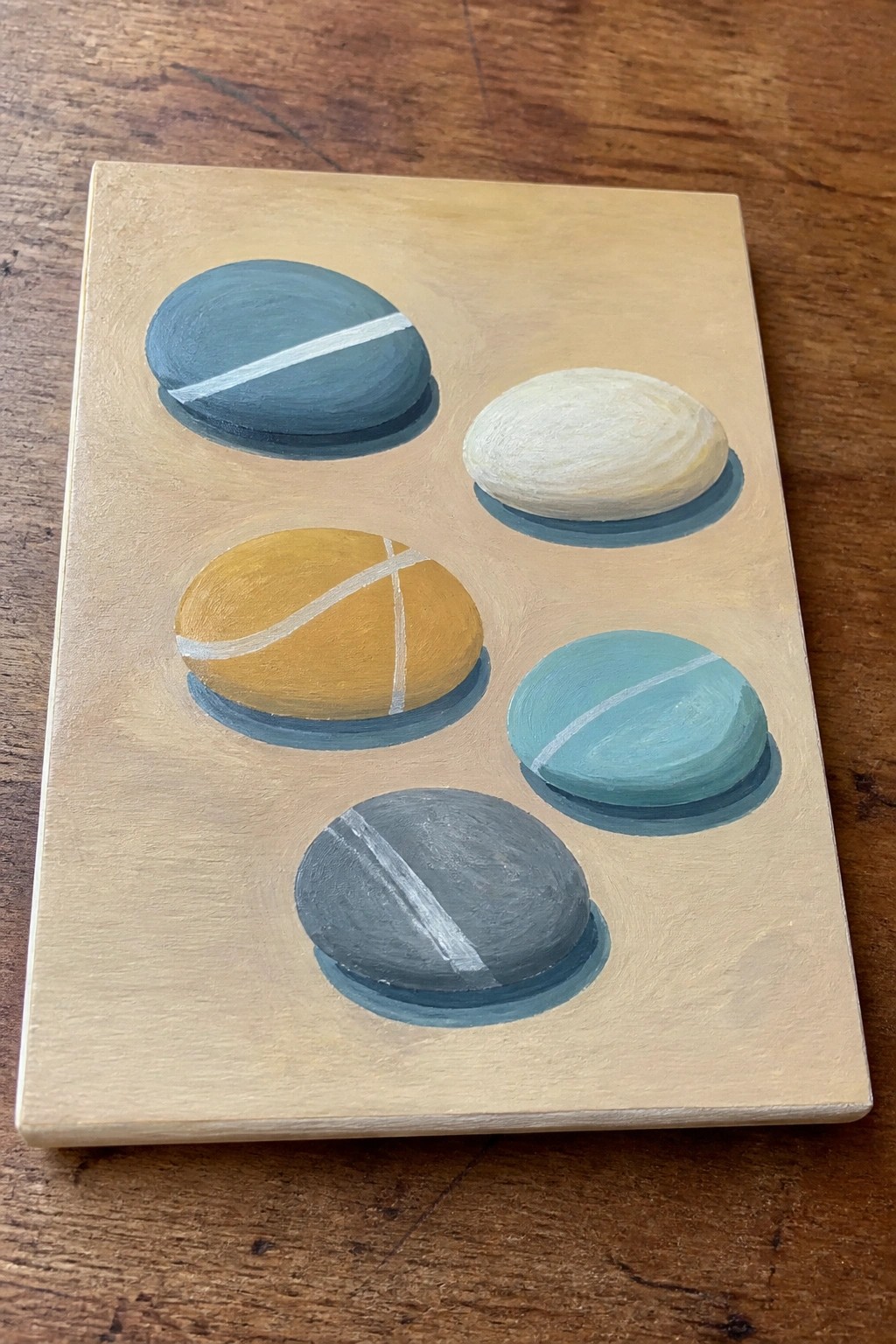 Five colorful pebbles with white stripes on a beige painted background
