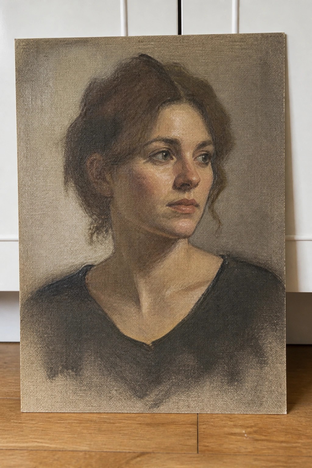 Oil painting of woman with brown hair in black V-neck top on canvas floor.