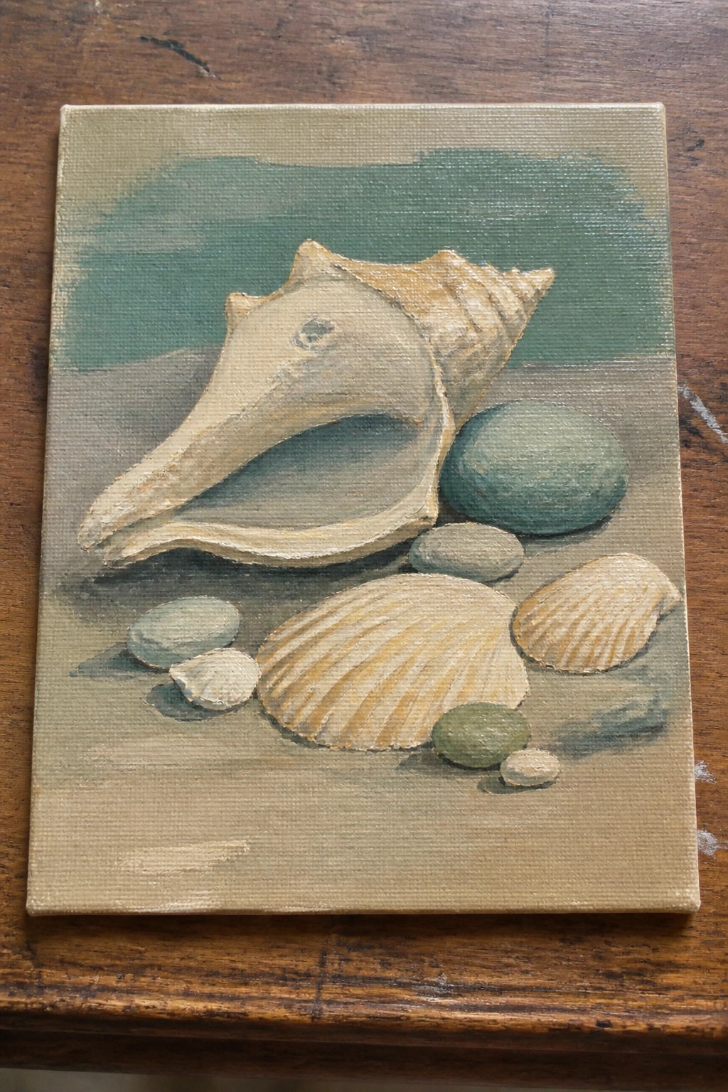 Acrylic painting of large conch shell with smaller seashells and pebbles on sand.