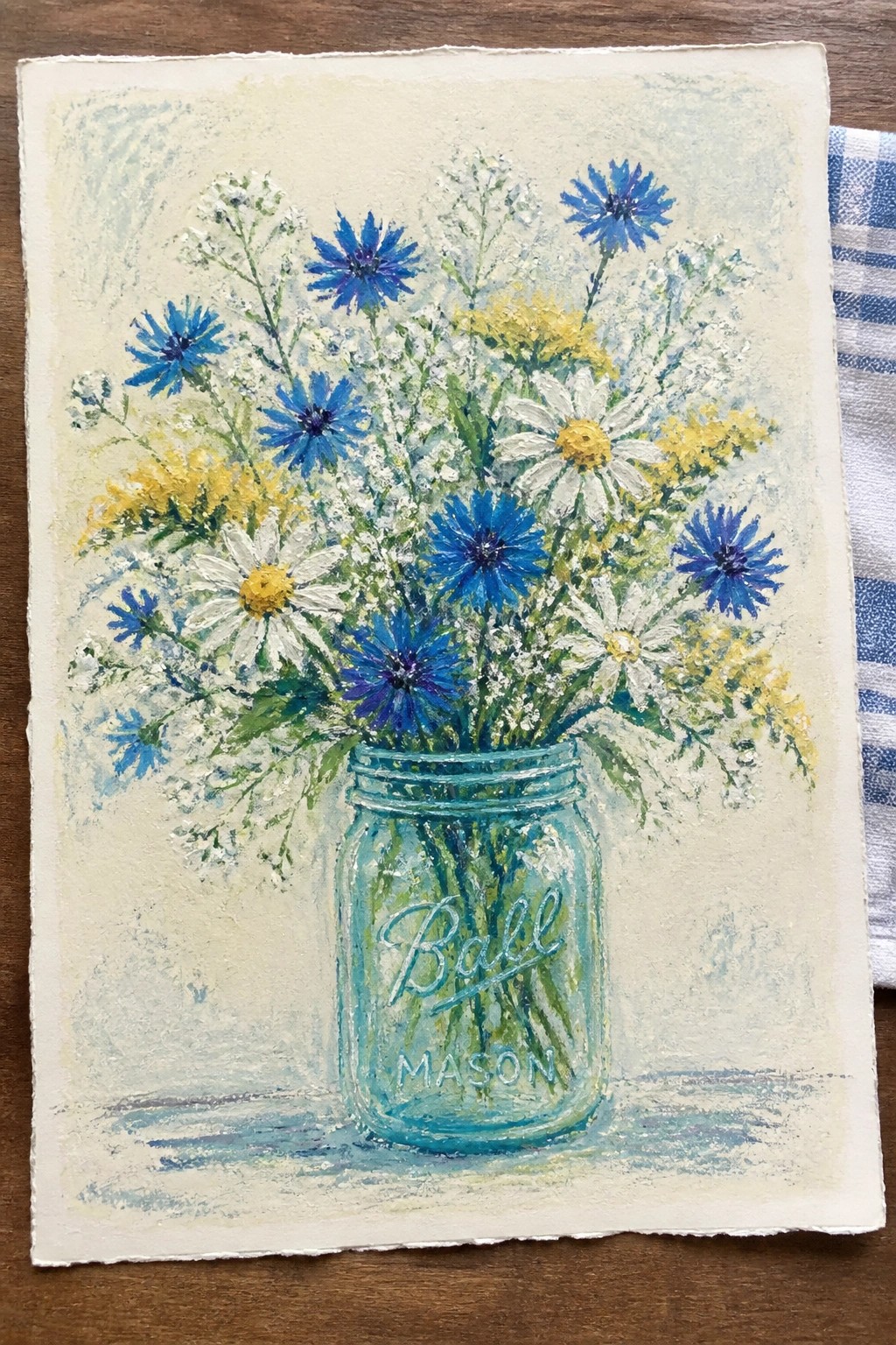 Colorful wildflowers in turquoise Ball Mason jar on wooden surface, painted style