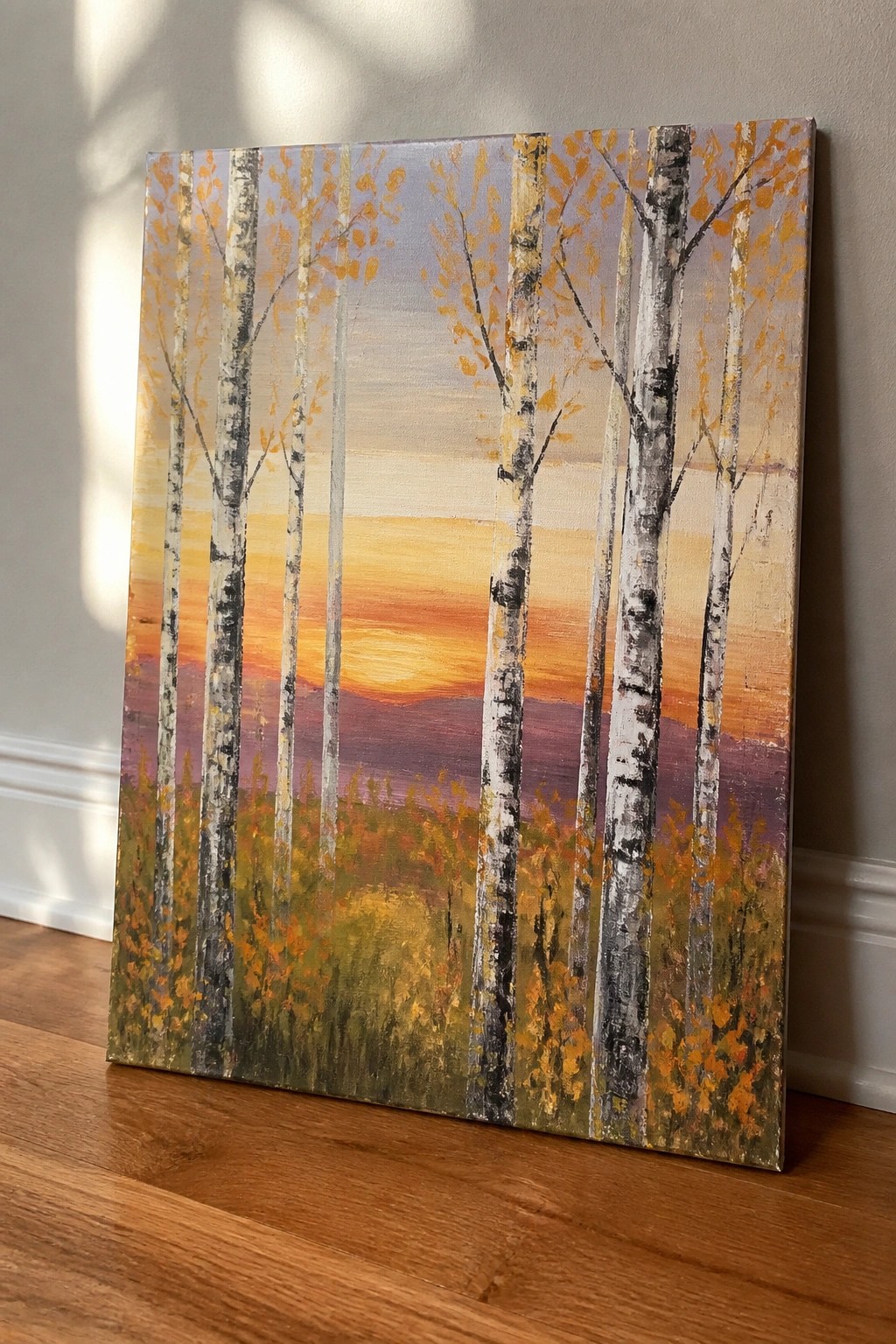 Birch trees with yellow leaves before a vibrant orange and purple sunset landscape