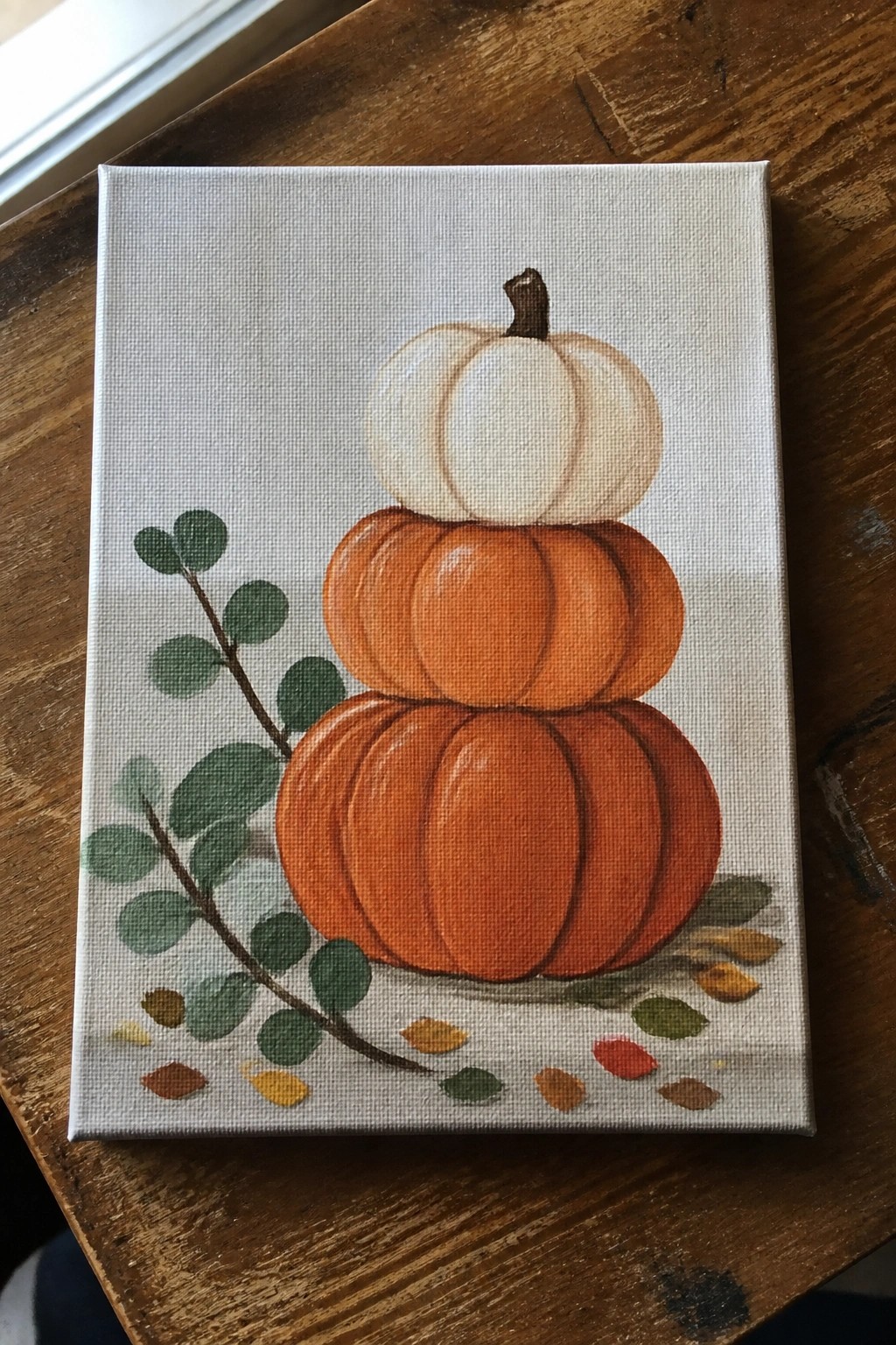Stacked orange and white pumpkins with green leaves on canvas
