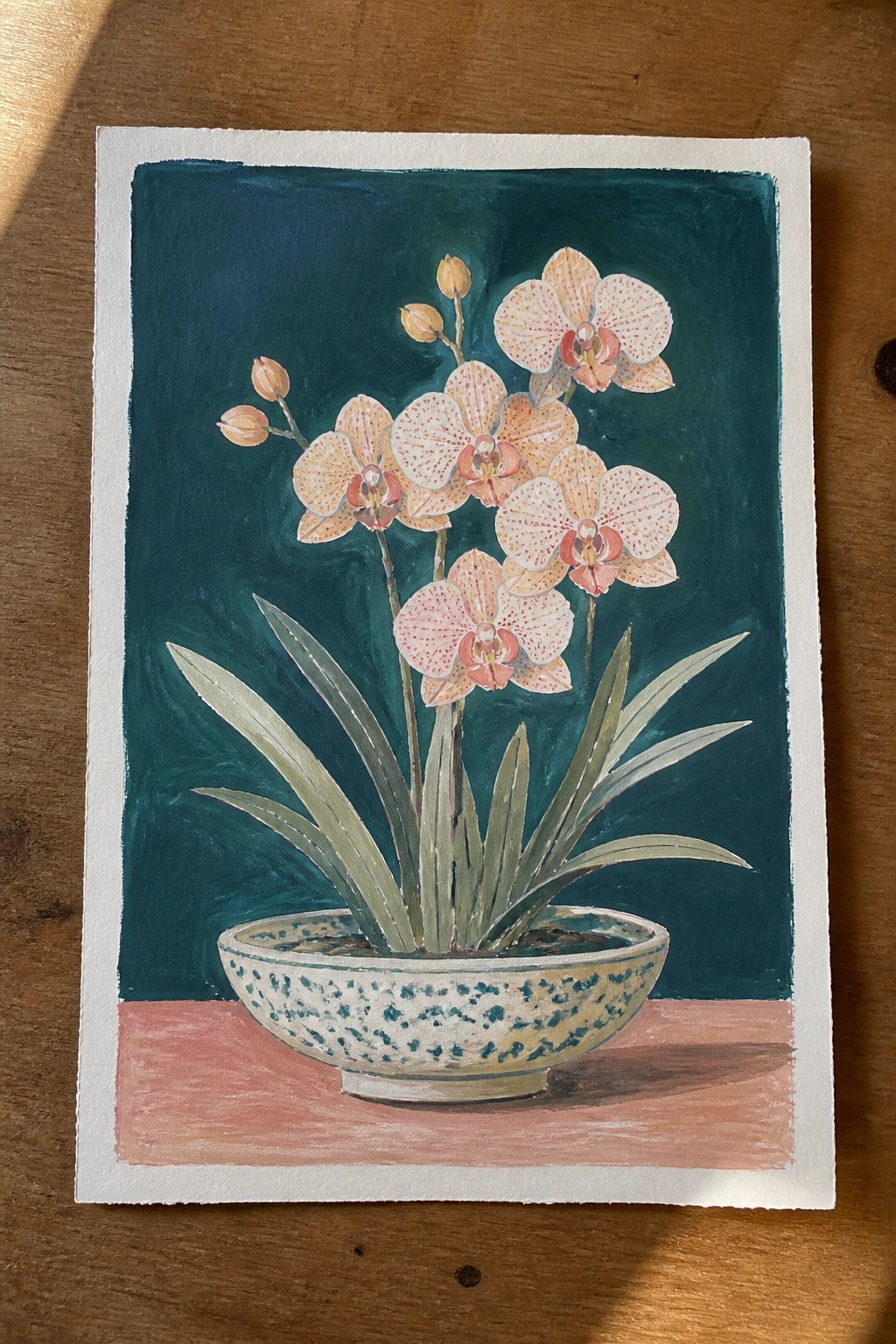 Watercolor of peach orchids in speckled bowl against teal background on pink surface